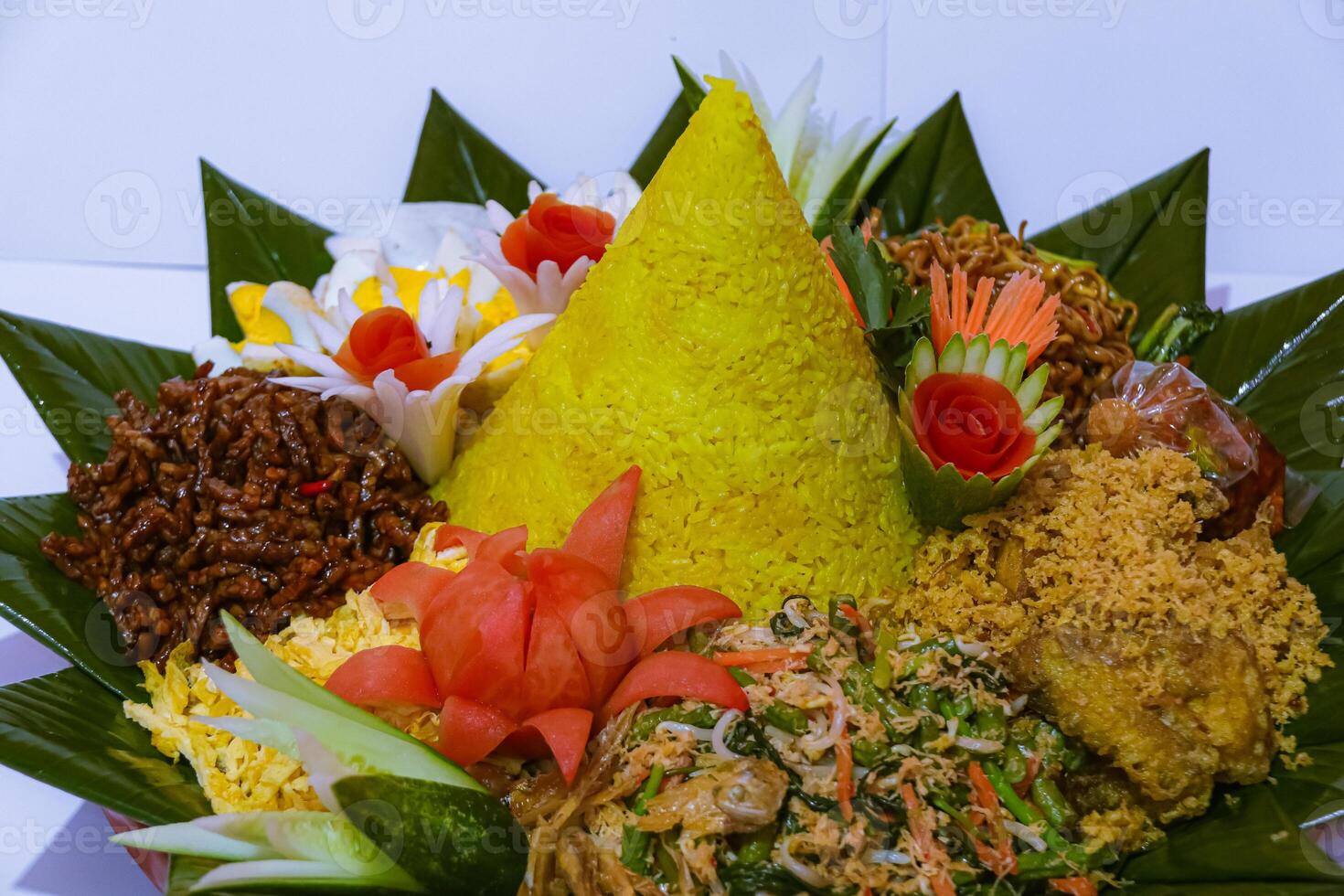 Tumpeng rice with various side dishes around it, a typical Indonesian cone-shaped rice dish photo