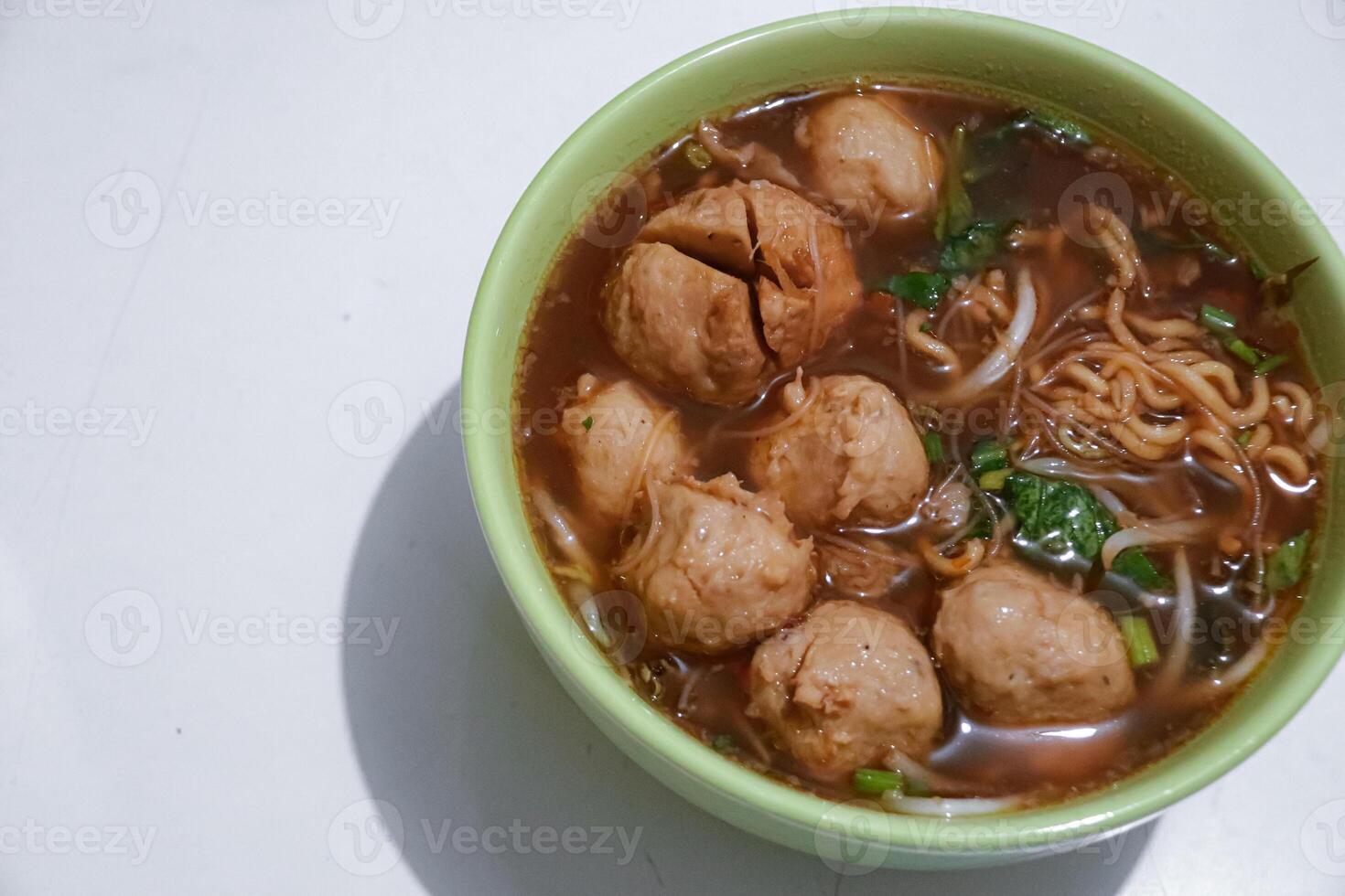 close up meatballs in bowl with vegetable toppings and noodles photo