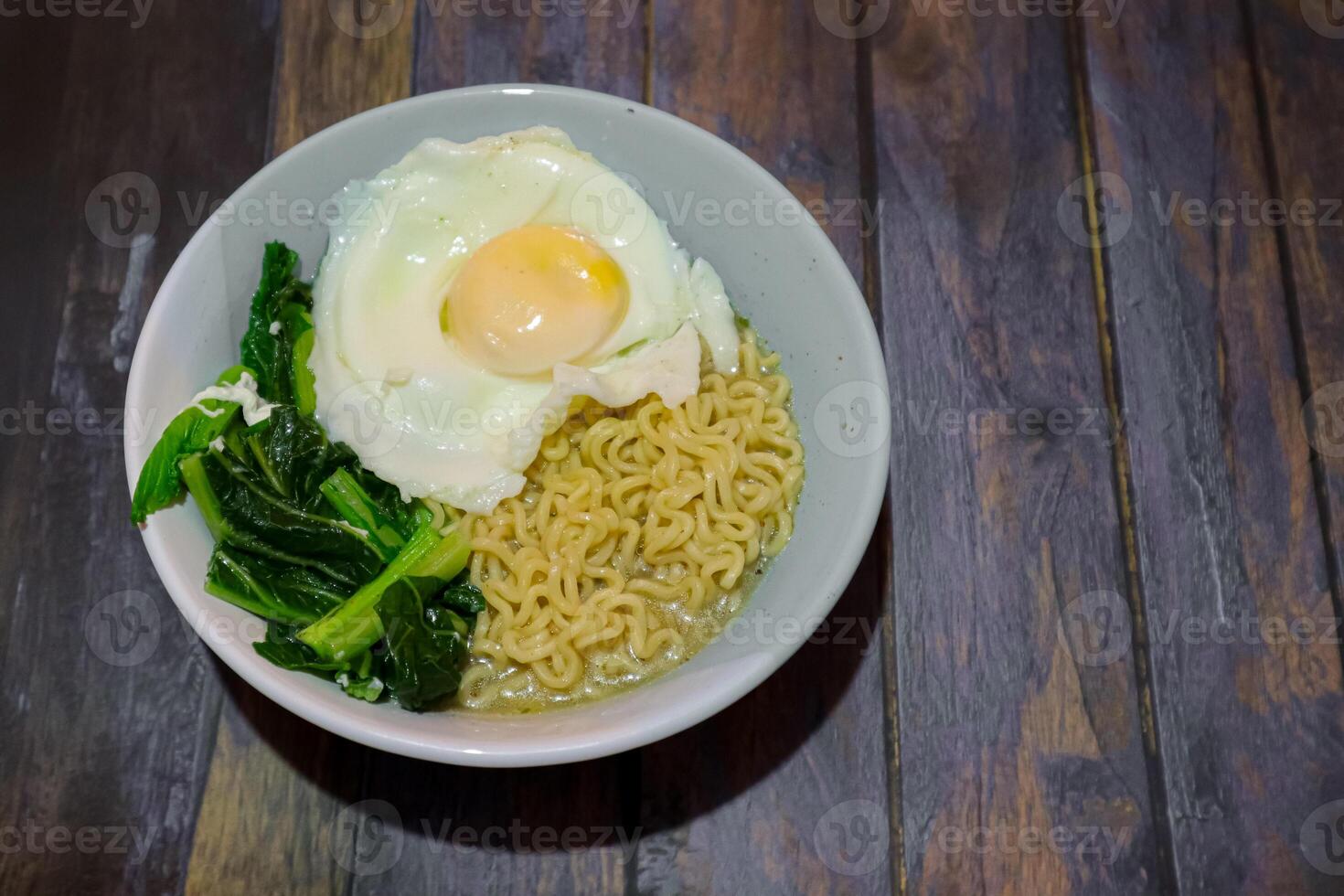 noodles in a bowl with sunny side up egg and vegetables photo