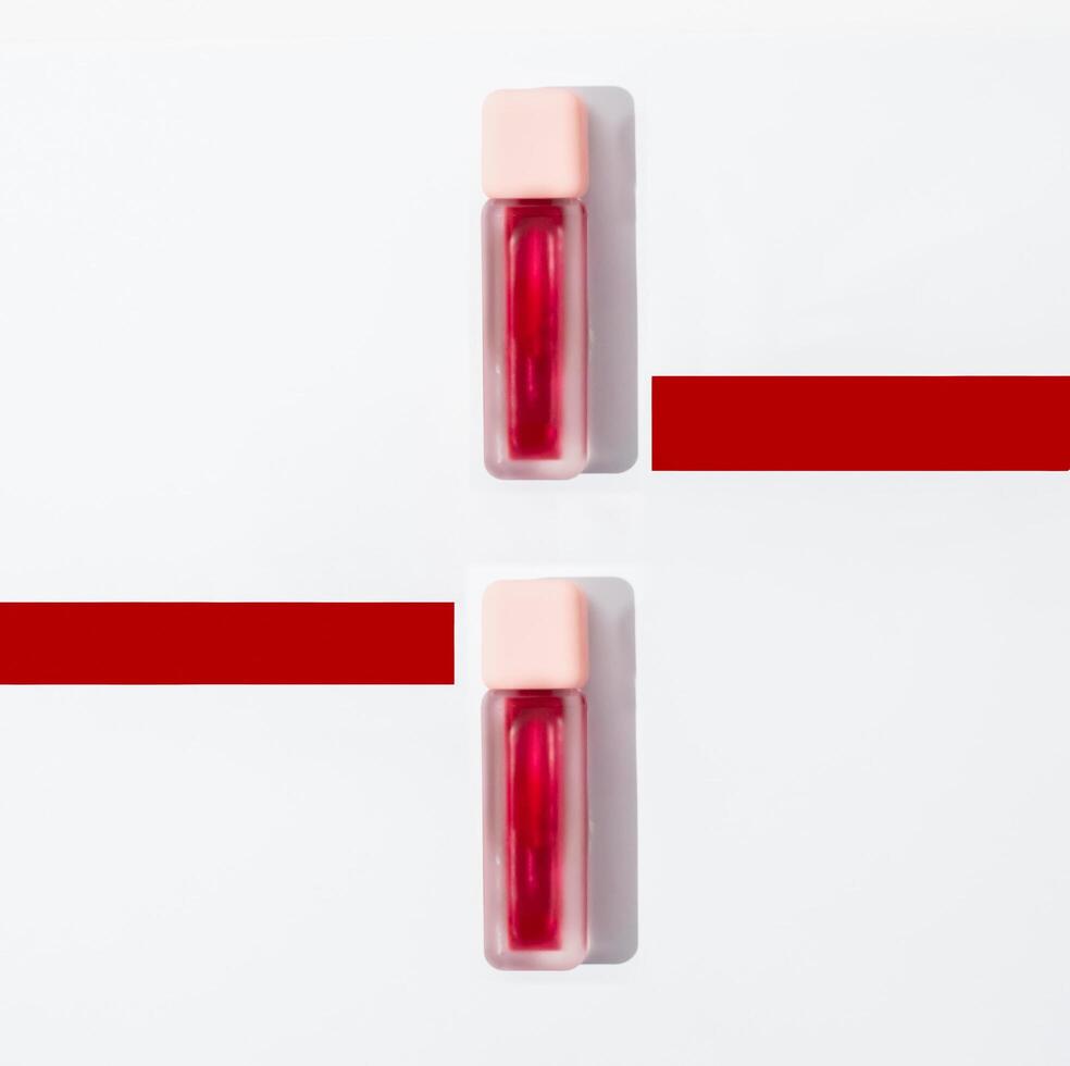 Two bottles of lip gloss on a white surface photo