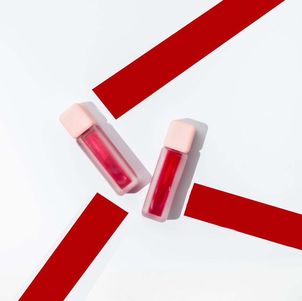 Two bottles of lip gloss on a white surface photo
