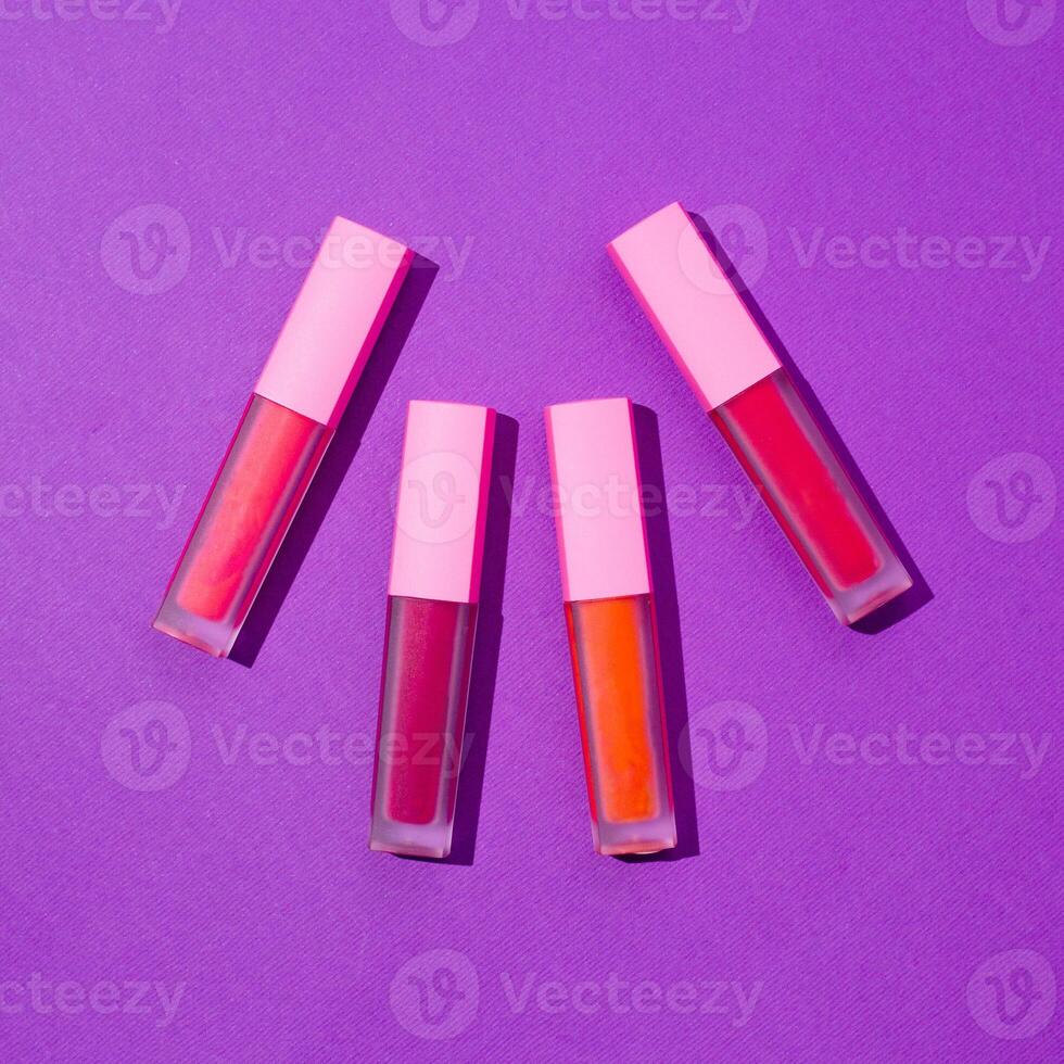 Three lip glosses on a purple surface photo