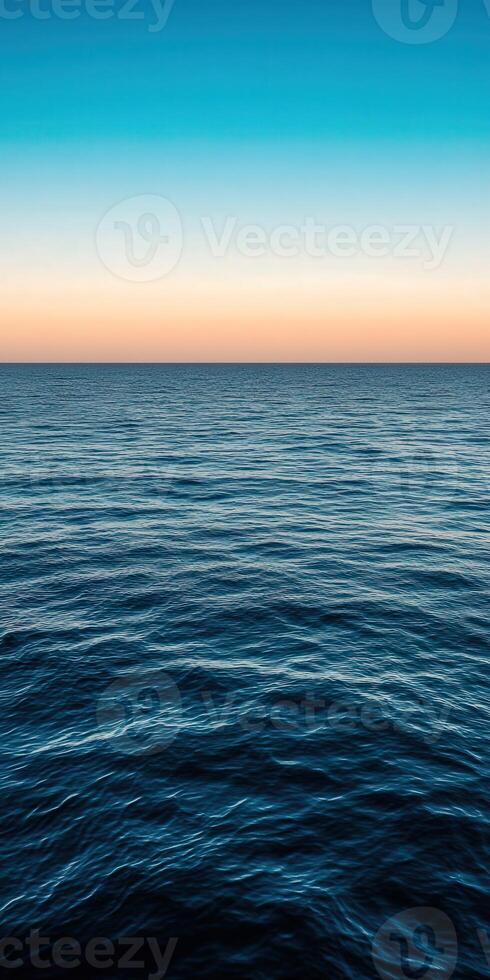 Calm ocean waves reflecting colorful sky at sunset over the horizon photo