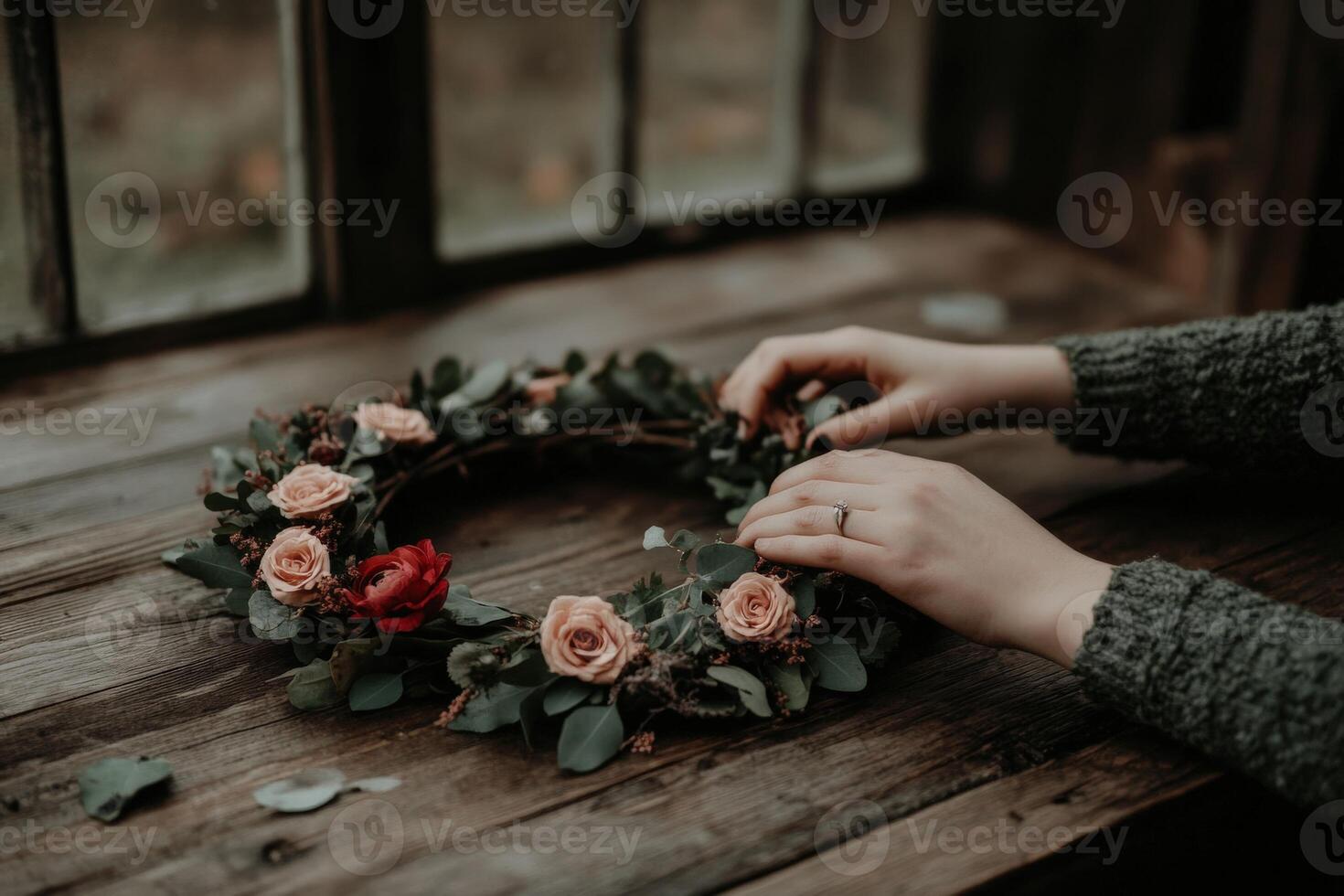 Hands assembling a floral wreath on a rustic wooden table photo