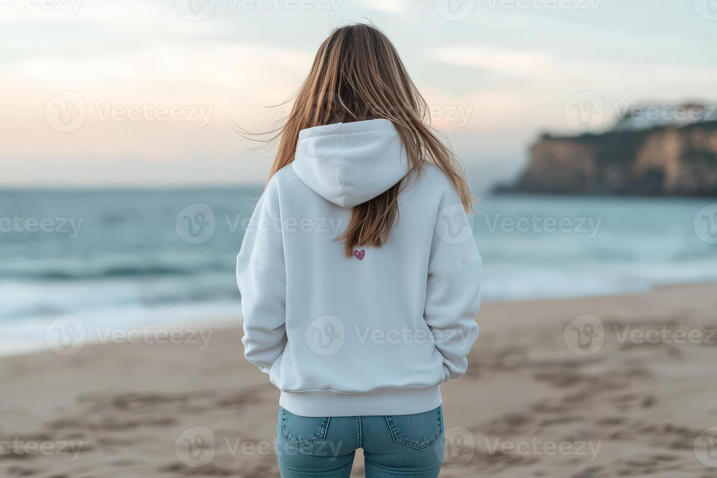 Woman in white hoodie standing at the beach during sunset photo