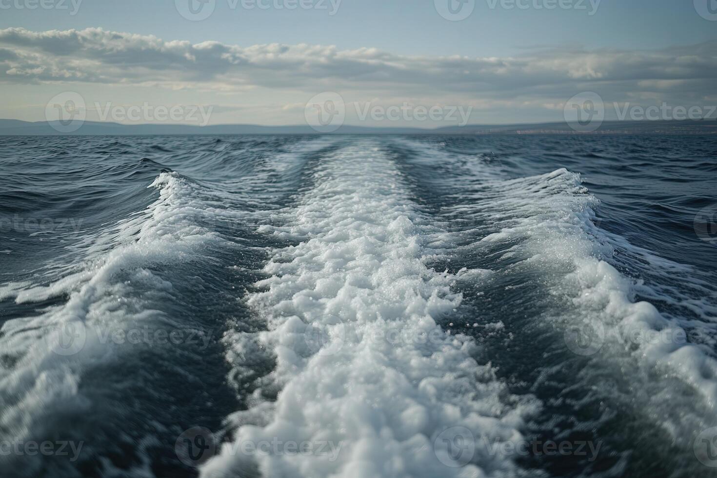 Waves create white water trails on a calm ocean during daytime photo