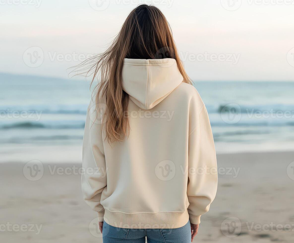 Woman standing on beach facing the ocean at sunset photo