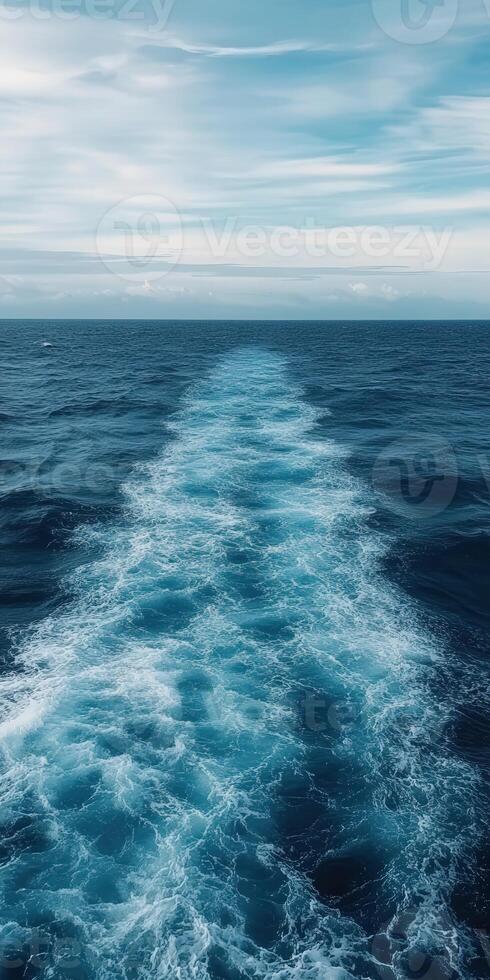 Ocean waves create a beautiful trail behind a moving vessel photo
