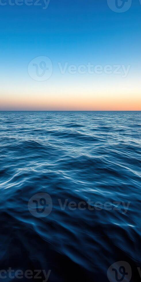 Calm ocean waves at sunset with a clear sky above the horizon photo