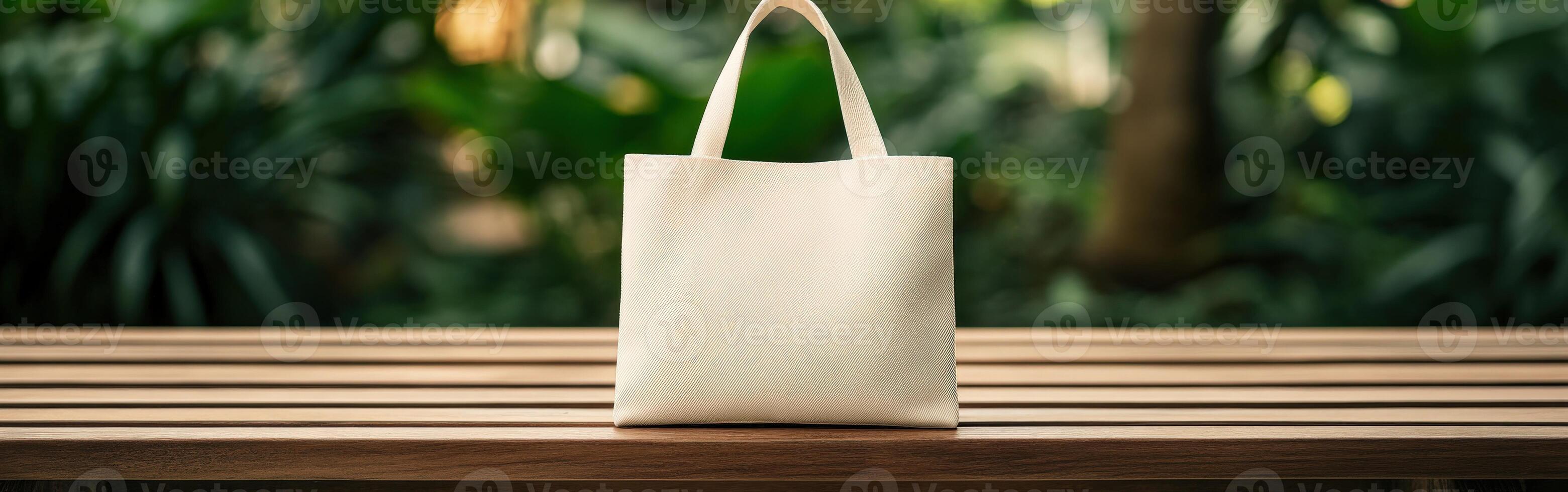 A simple fabric tote bag on a wooden table in a lush outdoor setting photo