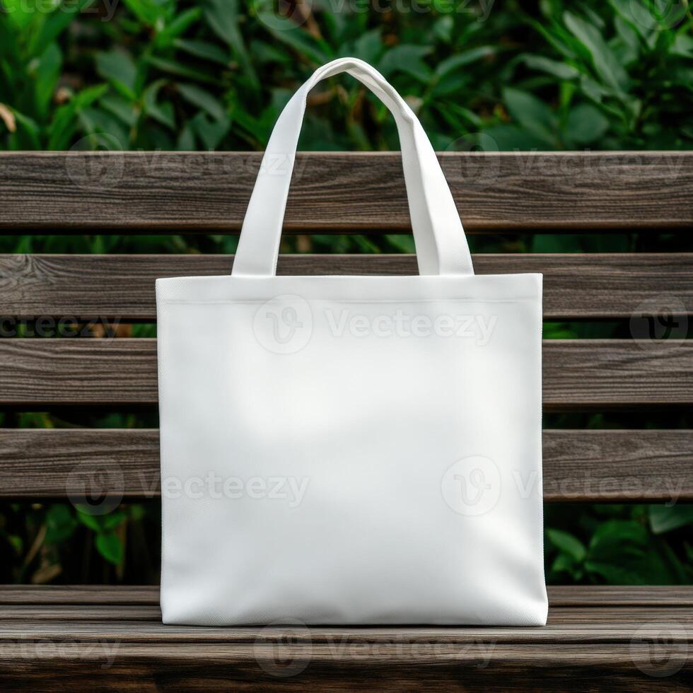 Simple white tote bag displayed on a wooden bench in a garden setting photo