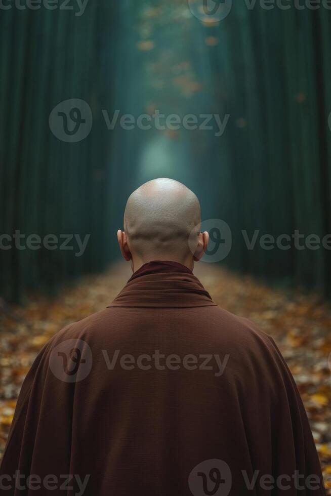A monk walking through a serene forest path surrounded by trees photo