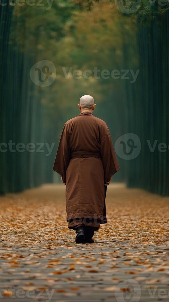A monk walking along a serene, leaf-covered path in autumn photo