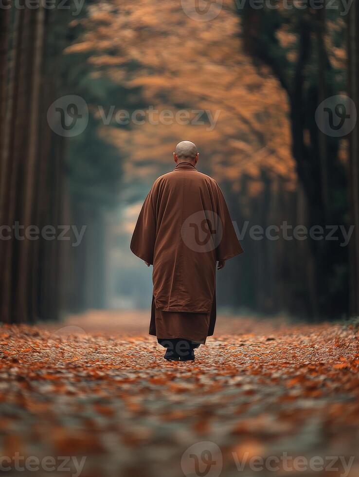A monk walking through a serene autumn forest path at twilight photo