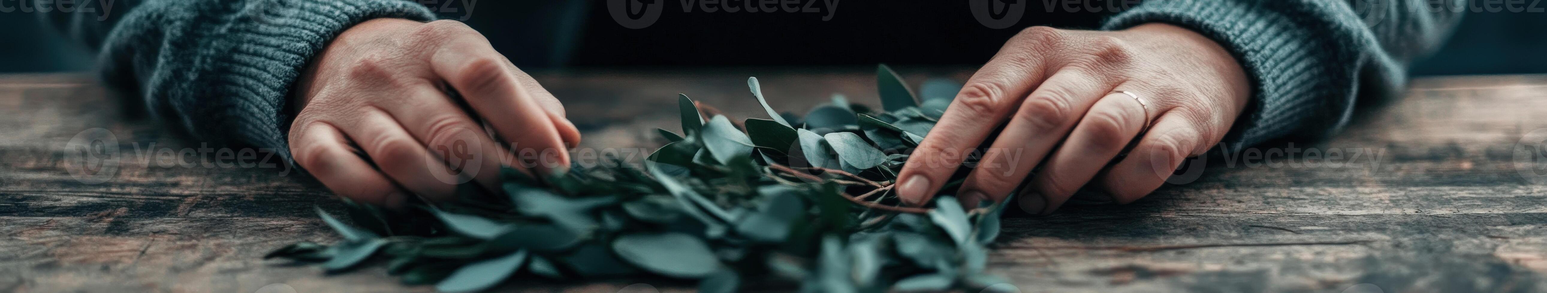 Hands arranging greenery on a rustic wooden table in natural light photo