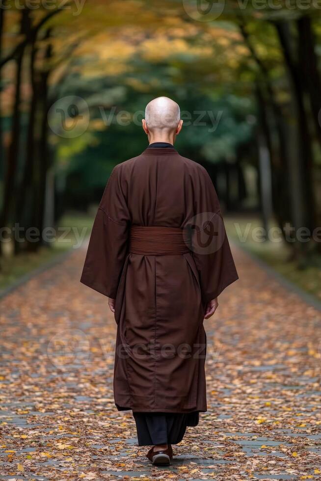 Buddhist monk walking along a serene autumn path in a tranquil forest photo