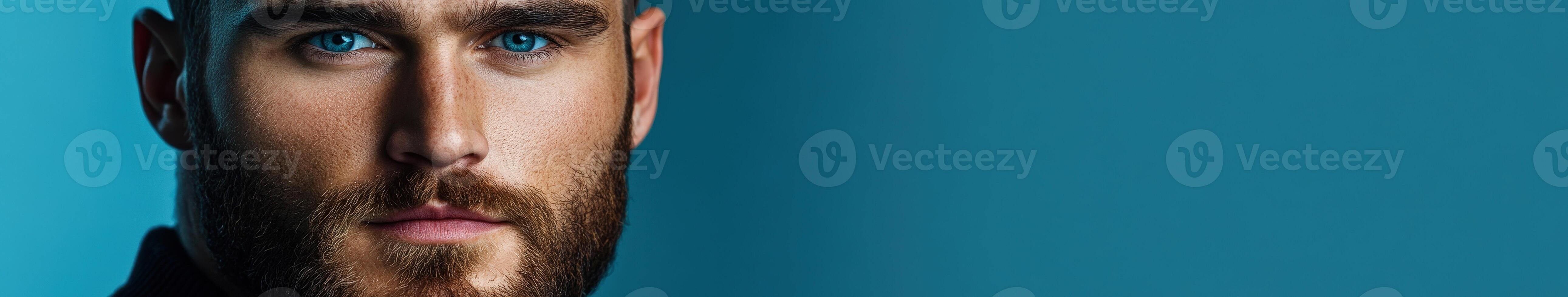 Bearded man with blue eyes and neutral expression on blue backdrop photo