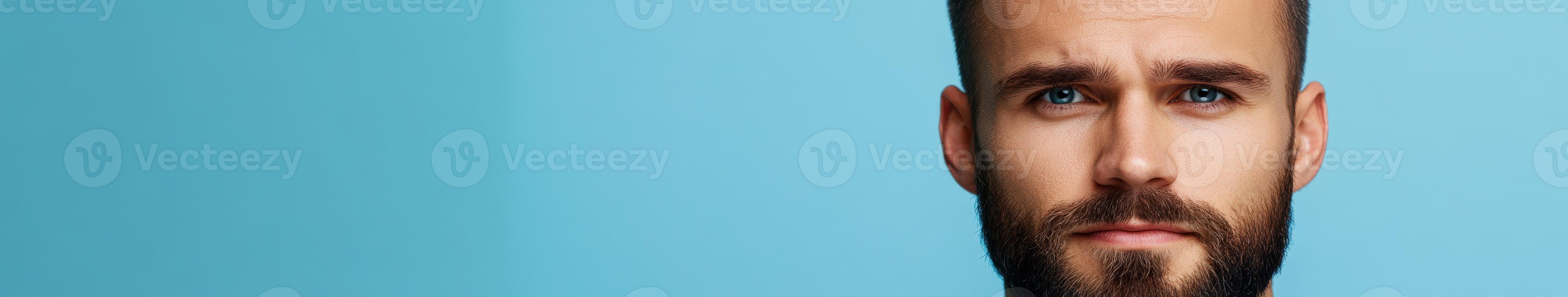 Young man with beard looking confidently against a bright blue background photo