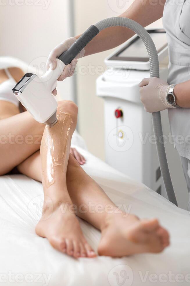 Beautician makes laser hair removal on woman's legs photo