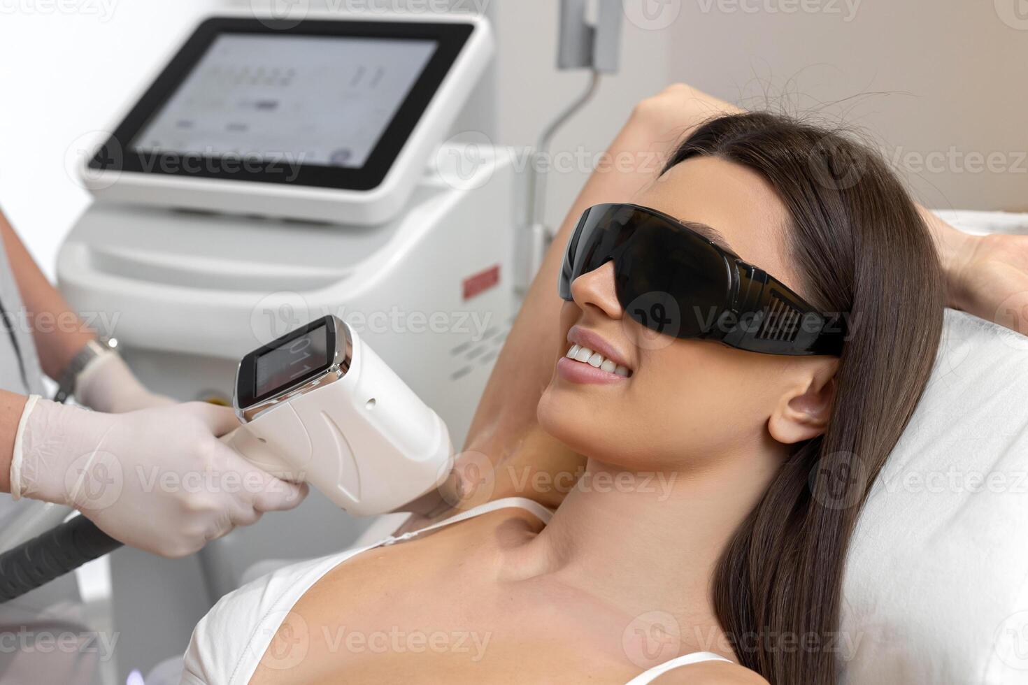 Cosmetologist make laser hair removal on woman's underarm photo