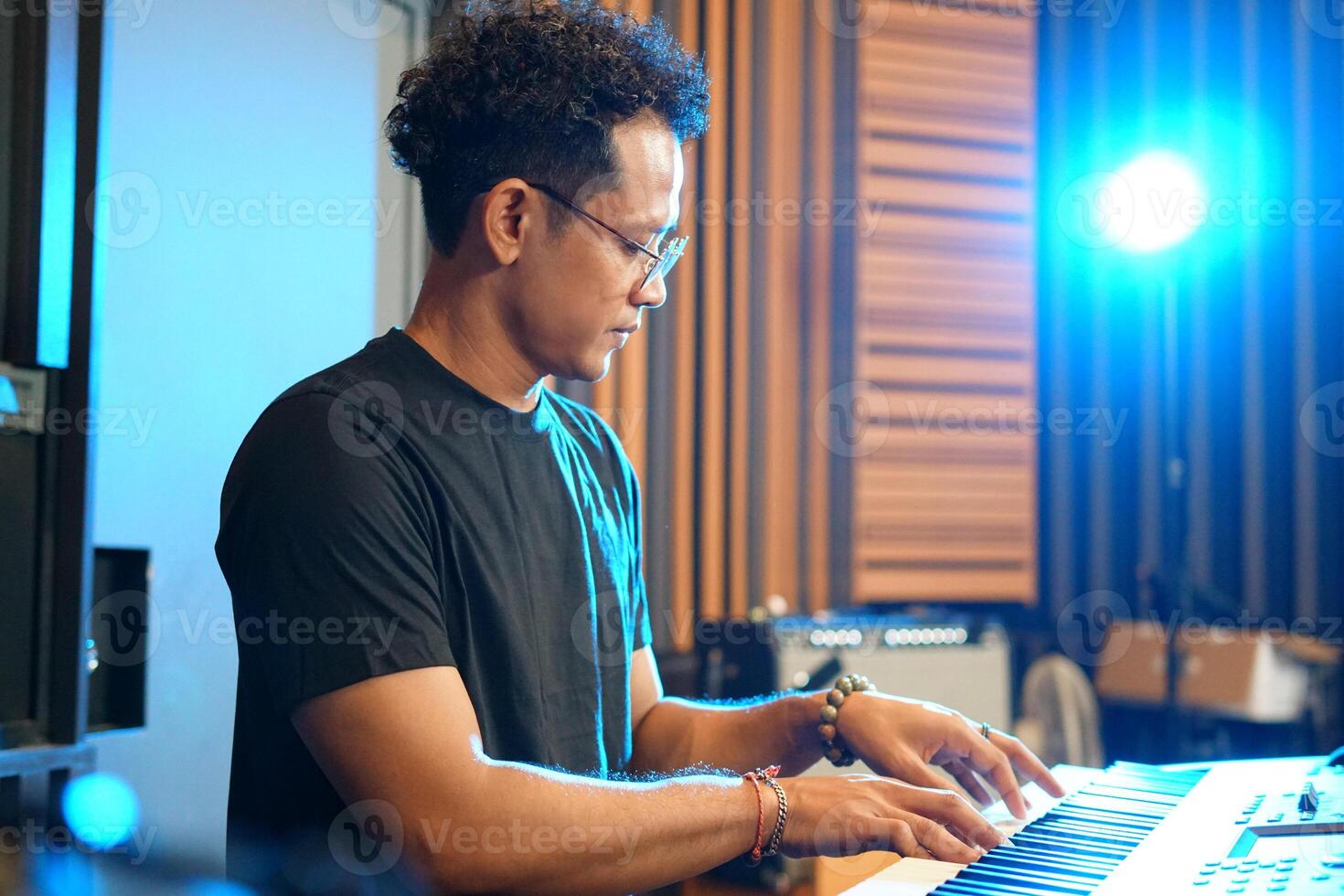 Musician playing music keyboard, Asian man playing piano and practicing in home studio photo