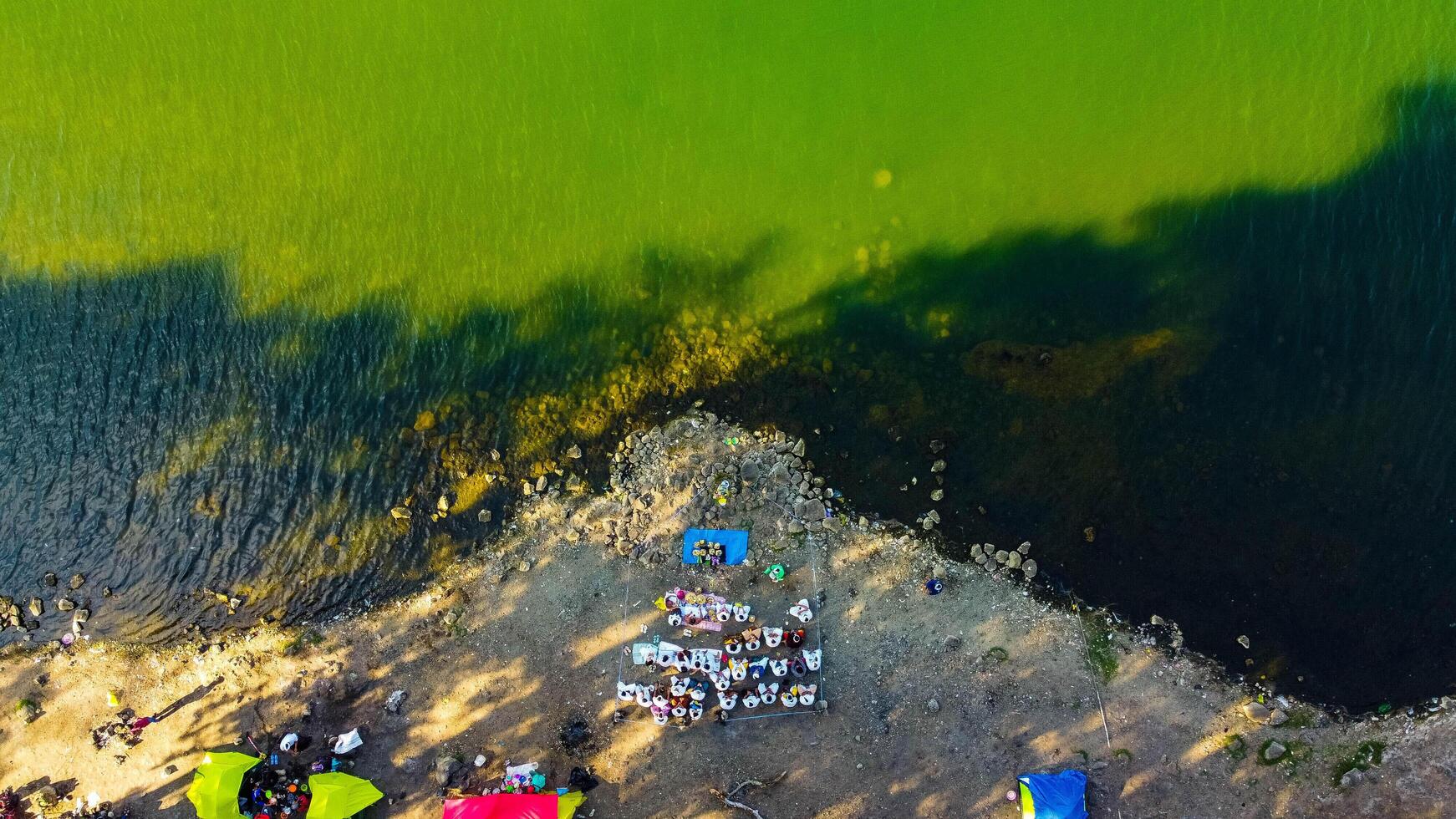 Aerial from the summit of Rinjani shows the stunning Segara Anak Lake below, Surrounded by vibrant blue skies and clouds, the lake's serene beauty stands out against the dramatic landscape. photo