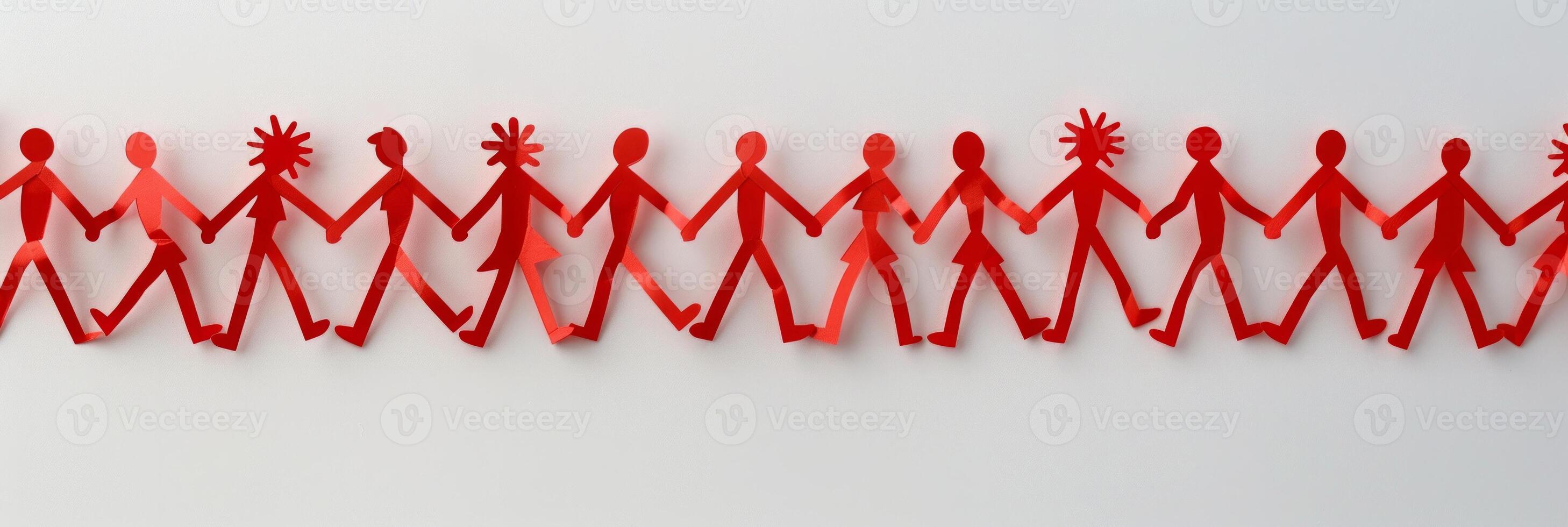 Top-down view of interconnected red paper cutout people holding hands, forming a chain photo