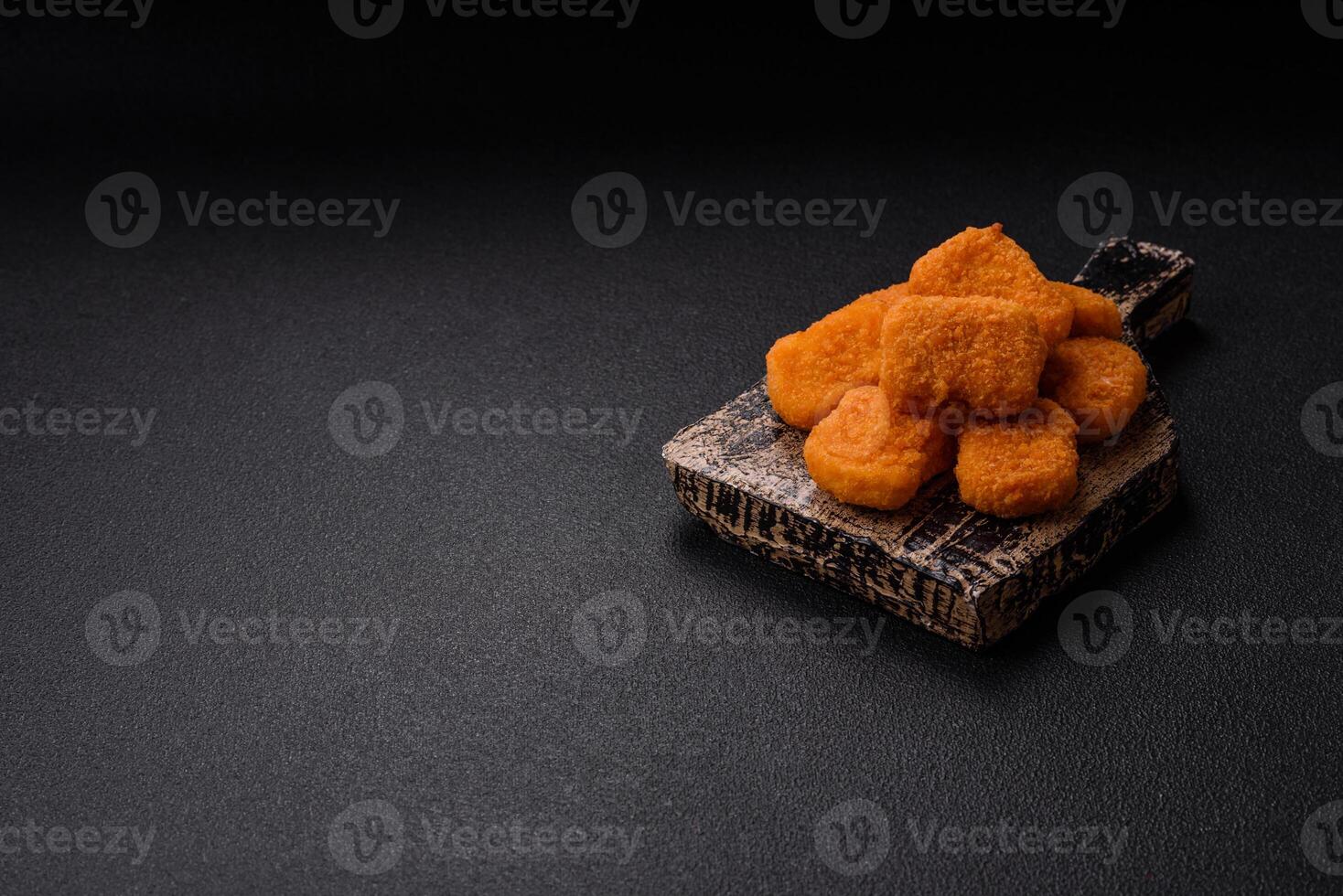 Delicious fresh crispy chicken nuggets on a dark concrete background photo