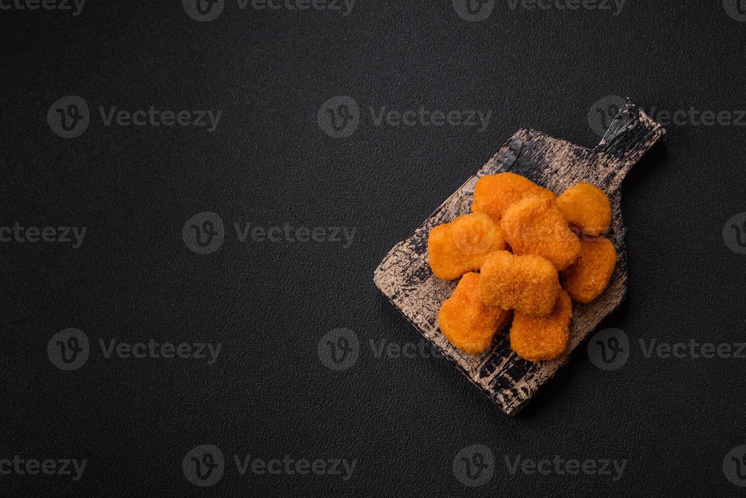 Delicious fresh crispy chicken nuggets on a dark concrete background photo