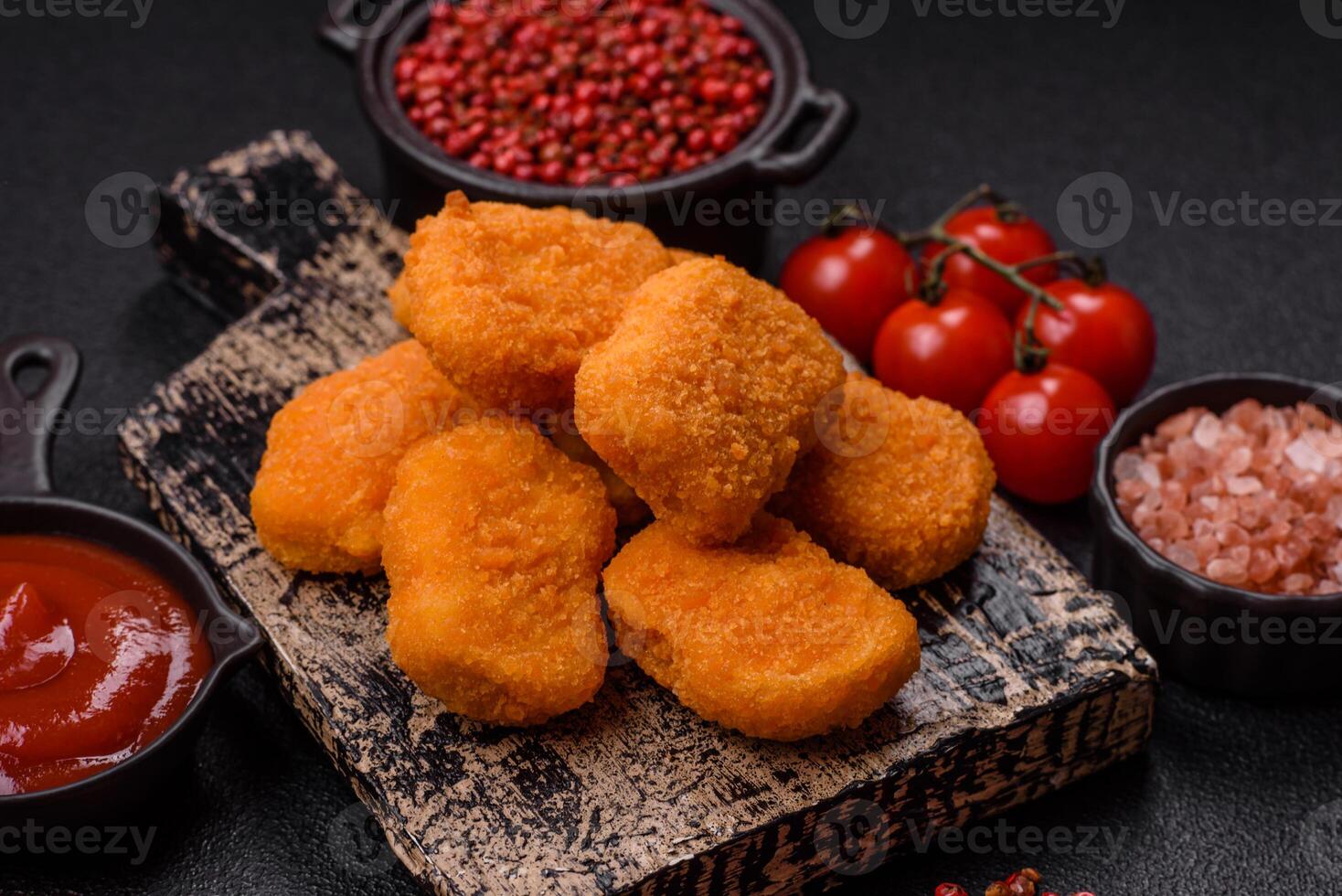 Delicious fresh crispy chicken nuggets on a dark concrete background photo
