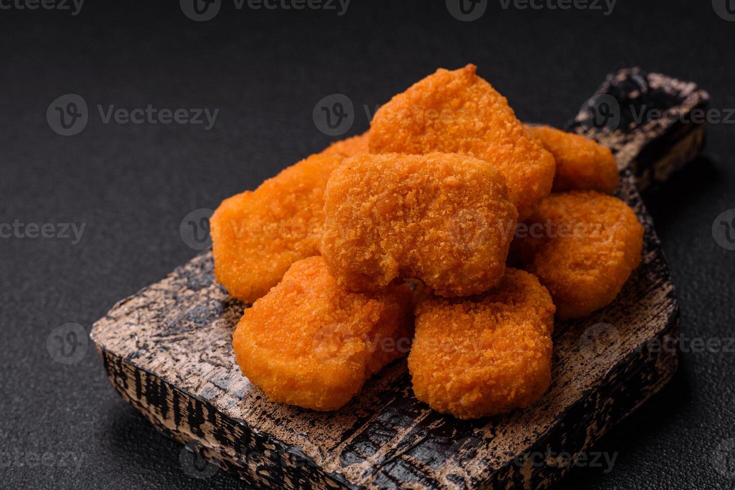 Delicious fresh crispy chicken nuggets on a dark concrete background photo