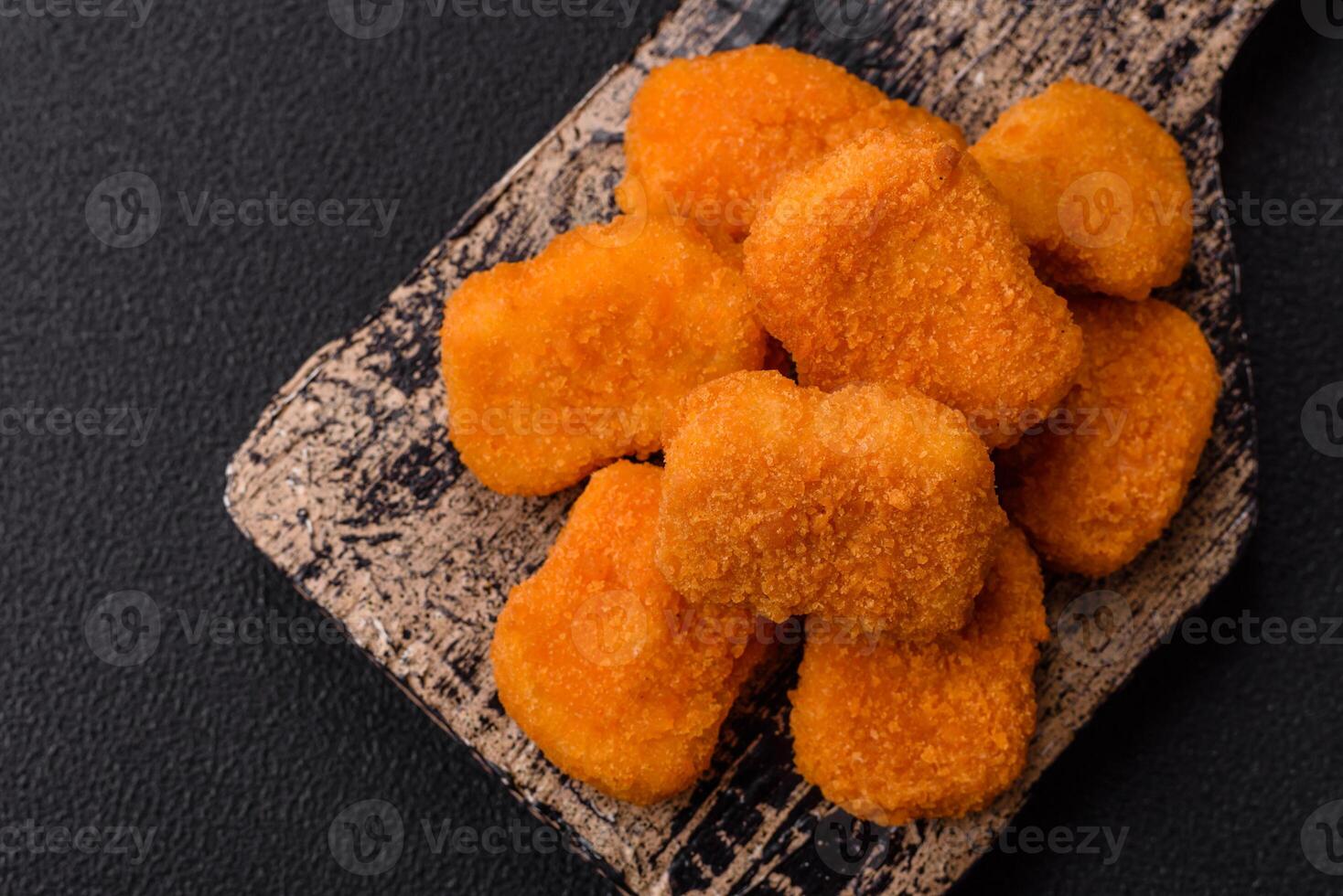 Delicious fresh crispy chicken nuggets on a dark concrete background photo