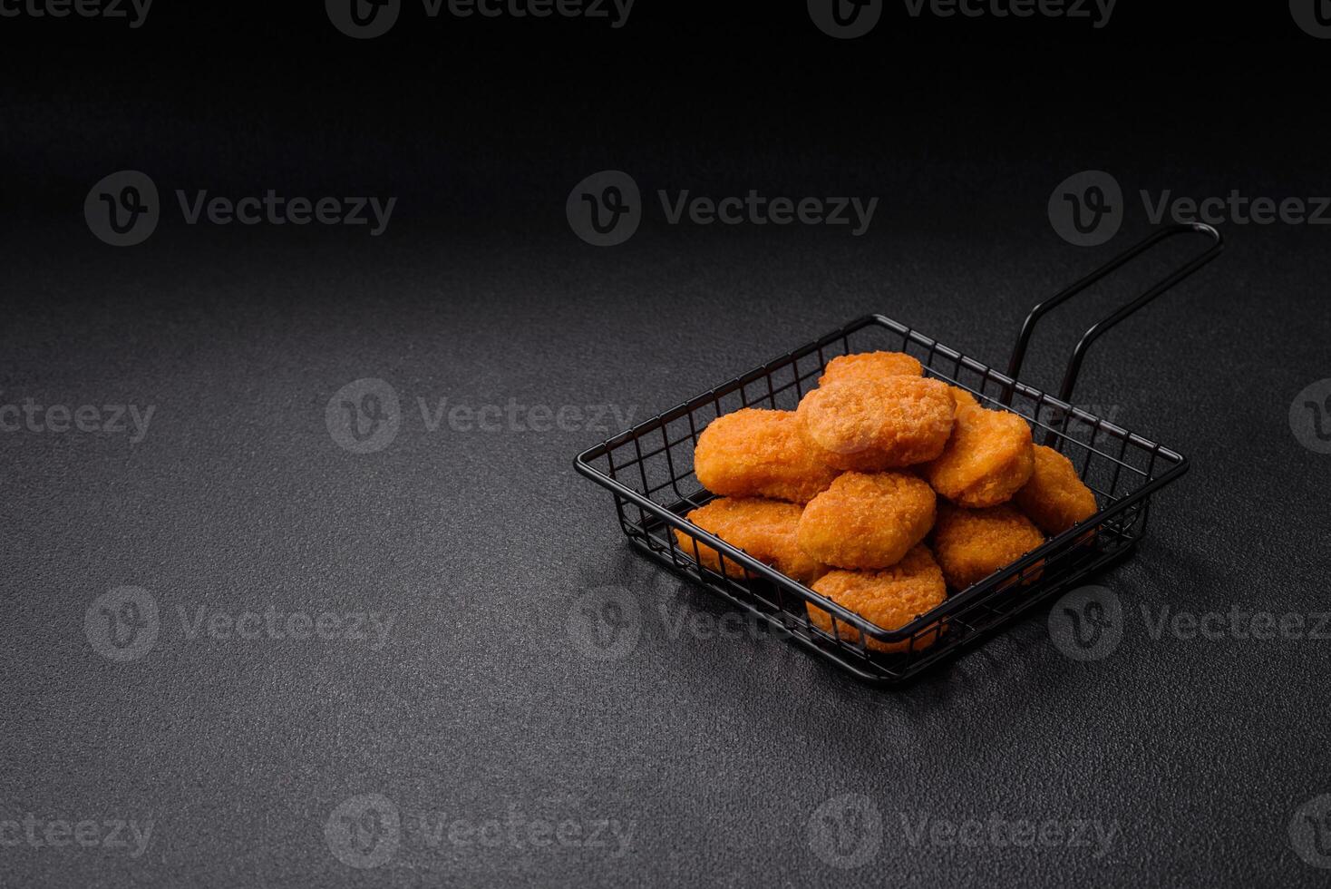 Delicious fresh crispy chicken nuggets on a dark concrete background photo