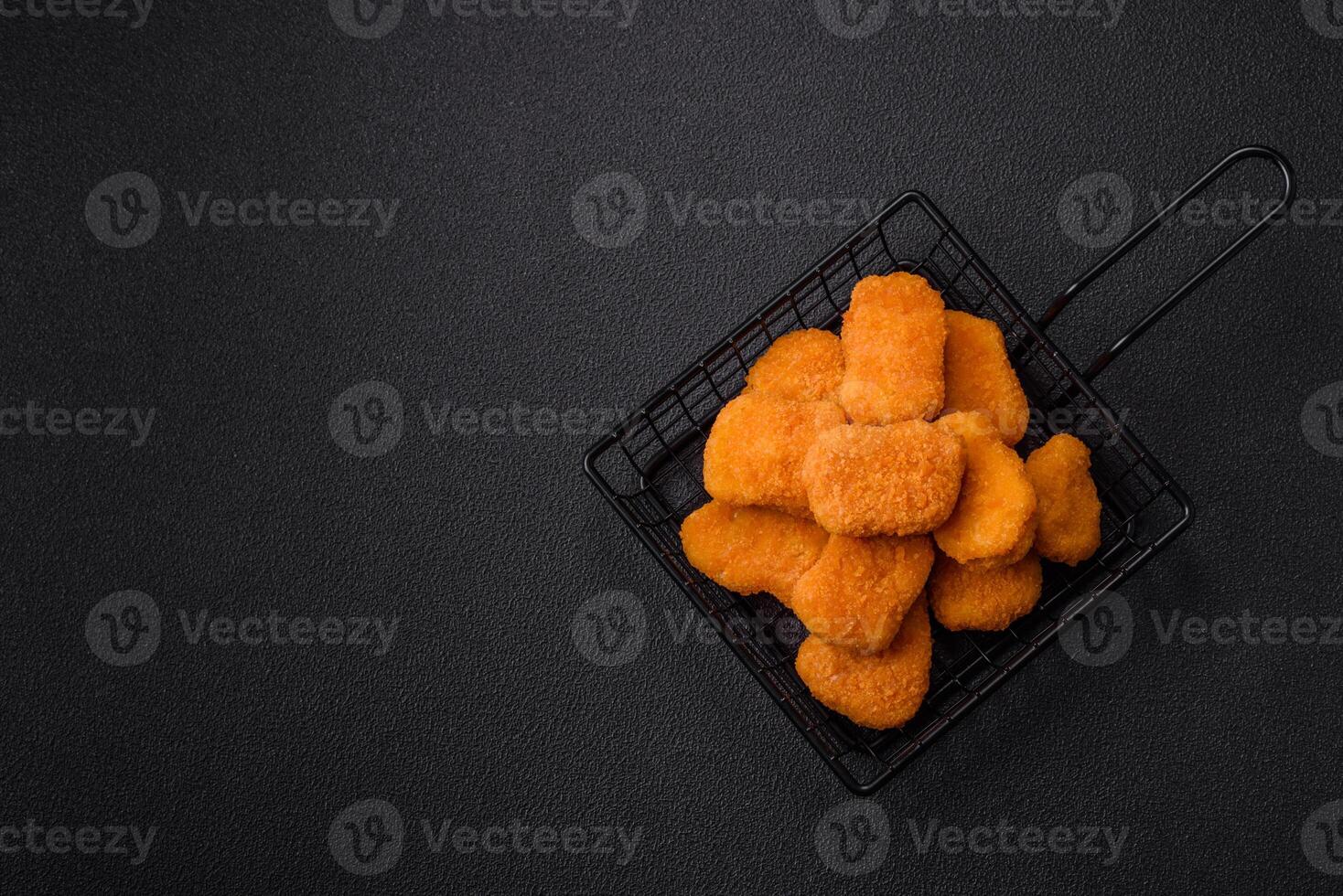 Delicious fresh crispy chicken nuggets on a dark concrete background photo