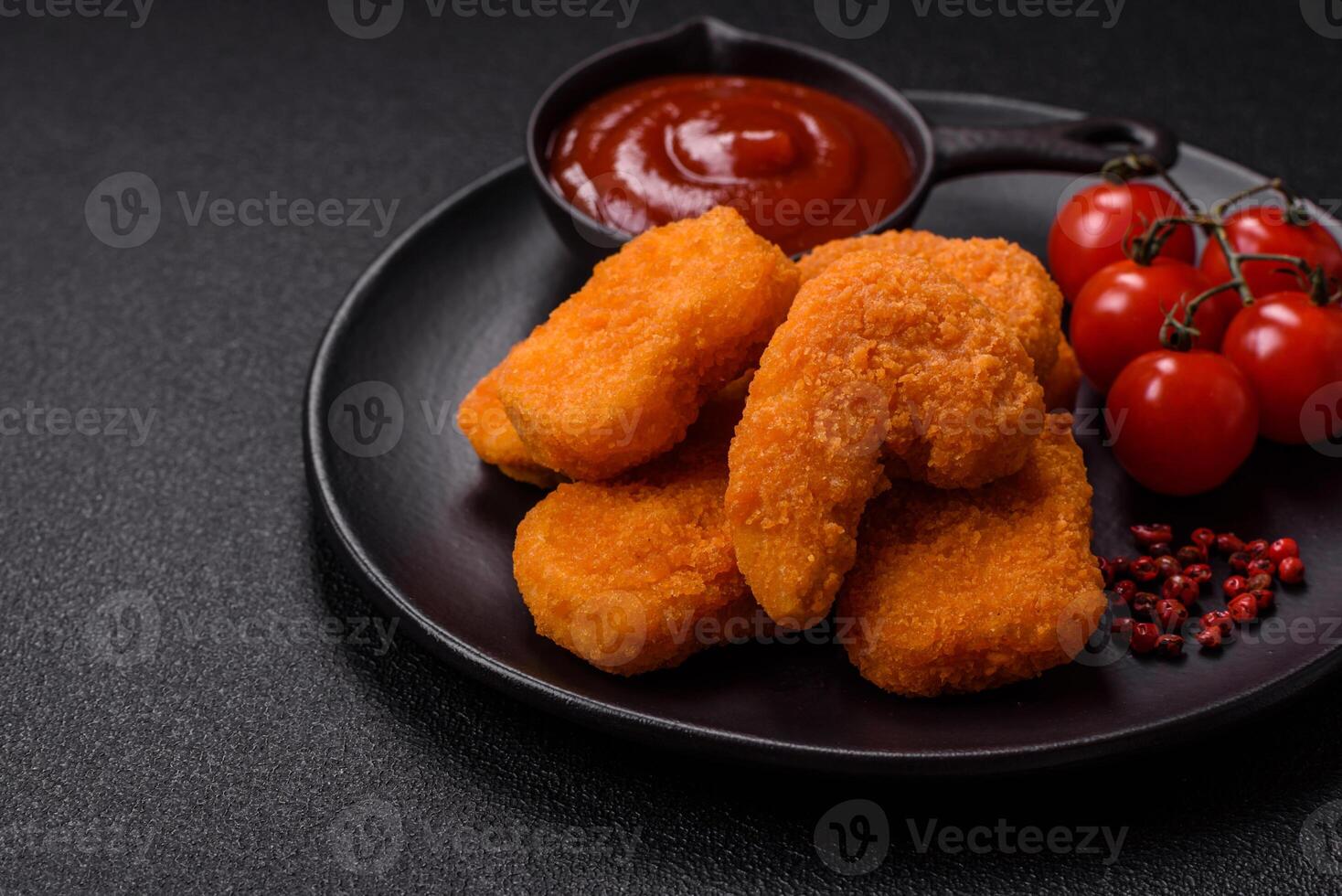 Delicious fresh crispy chicken nuggets on a dark concrete background photo