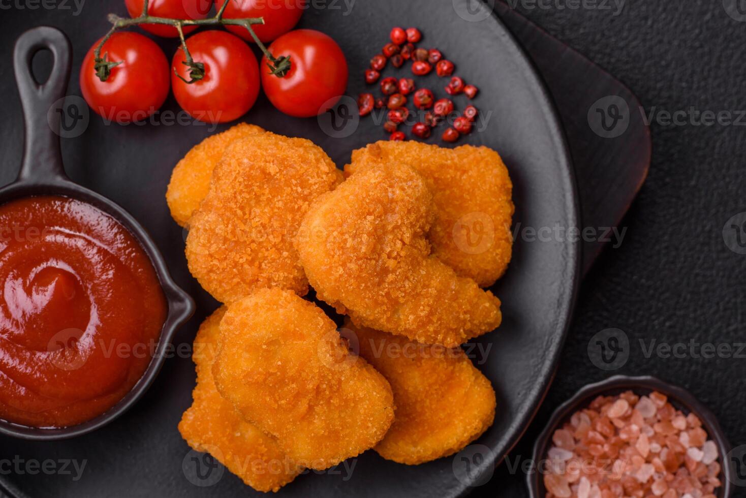 Delicious fresh crispy chicken nuggets on a dark concrete background photo