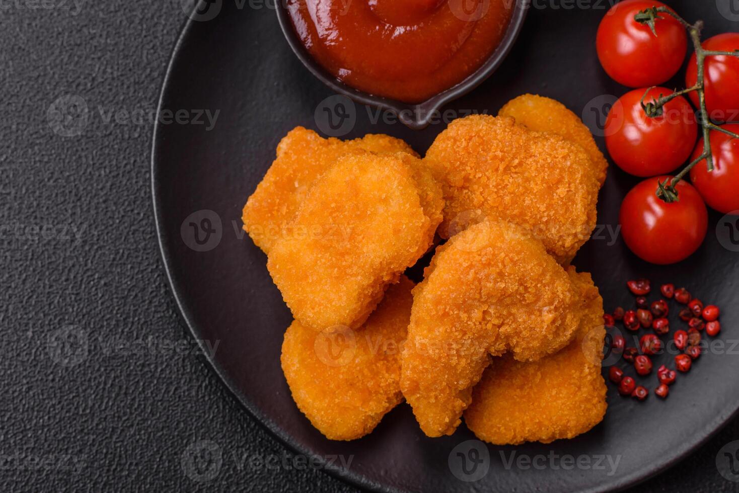Delicious fresh crispy chicken nuggets on a dark concrete background photo