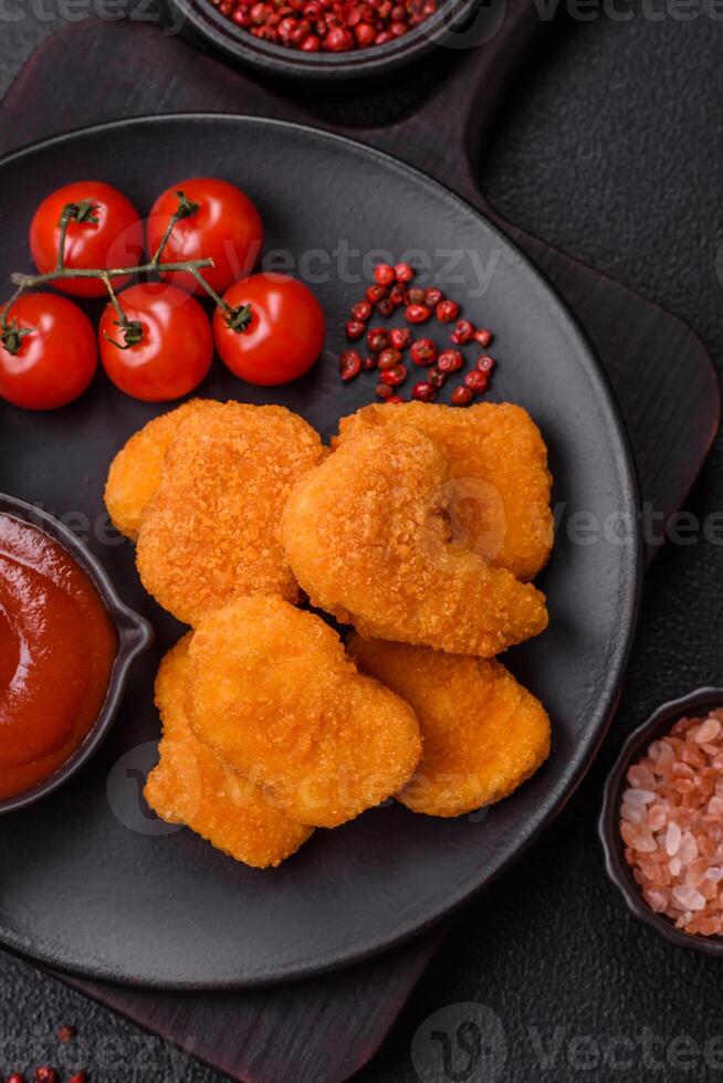 Delicious fresh crispy chicken nuggets on a dark concrete background photo