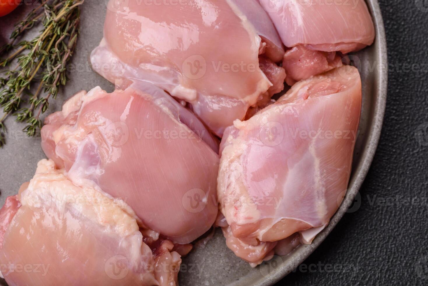Fresh raw chicken thigh fillets with salt, spices and herbs photo