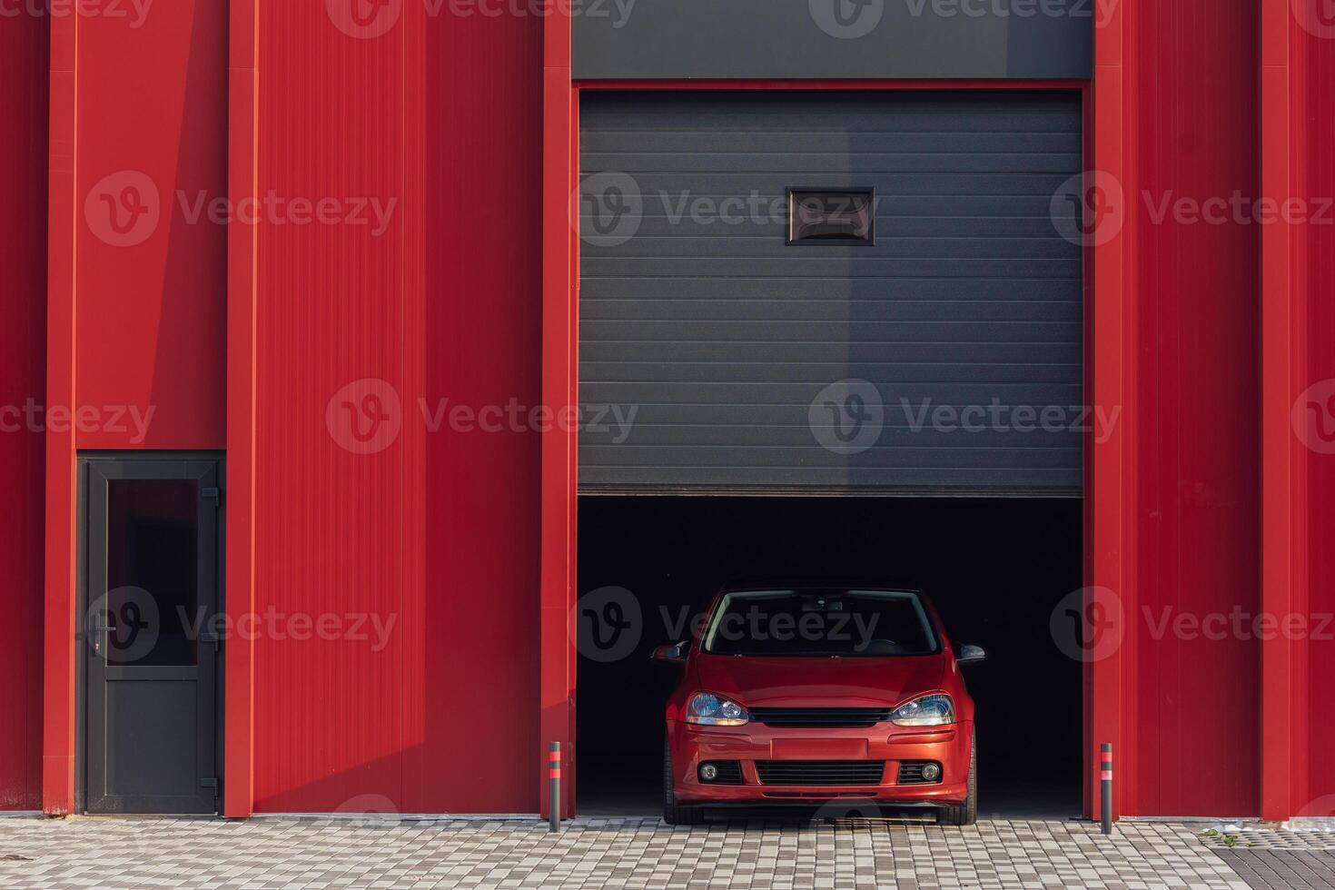 A red car is parked at the exit of a red garage photo