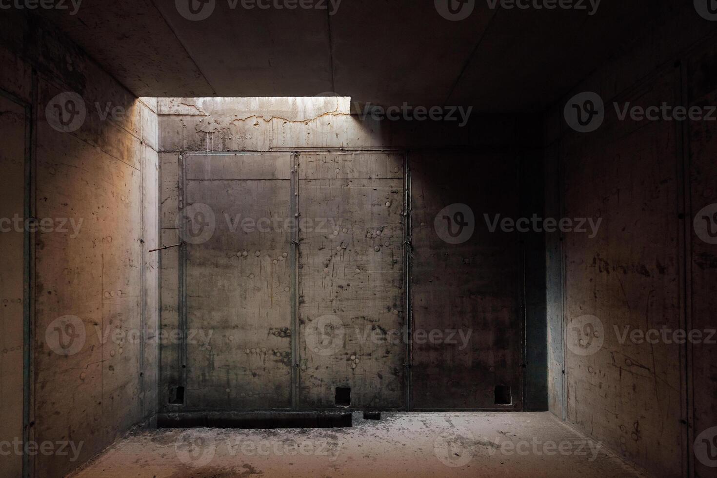 a dark room with concrete walls and a small light opening in the ceiling photo