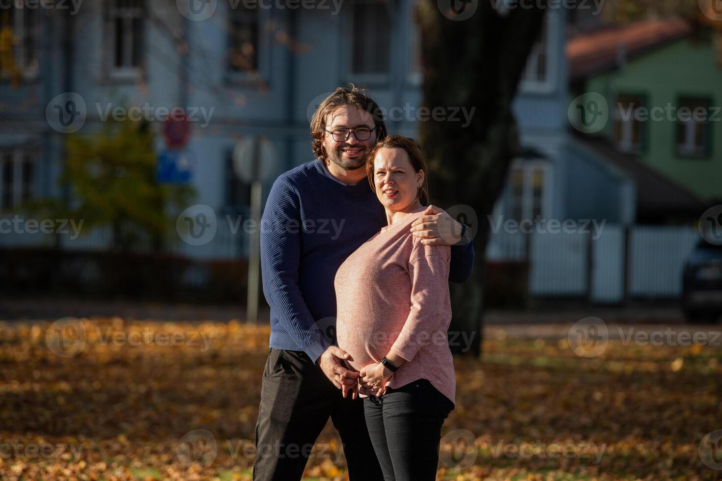 A man lovingly embraces his pregnant wife in the park, sharing a peaceful moment of warmth and affection photo