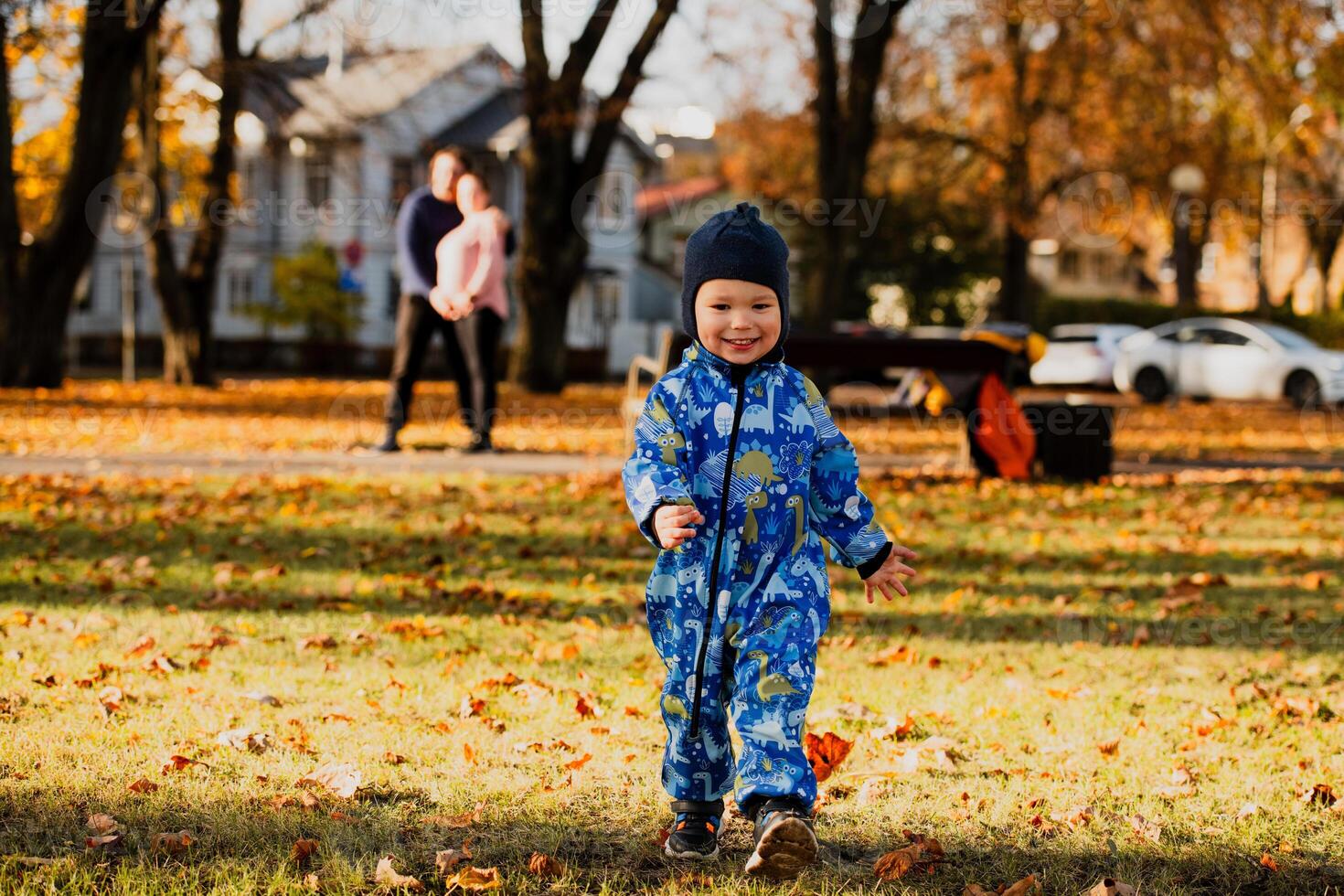 A joyful little boy in his winter coat and hat plays happily in the park, surrounded by the love and warmth of his smiling parents photo