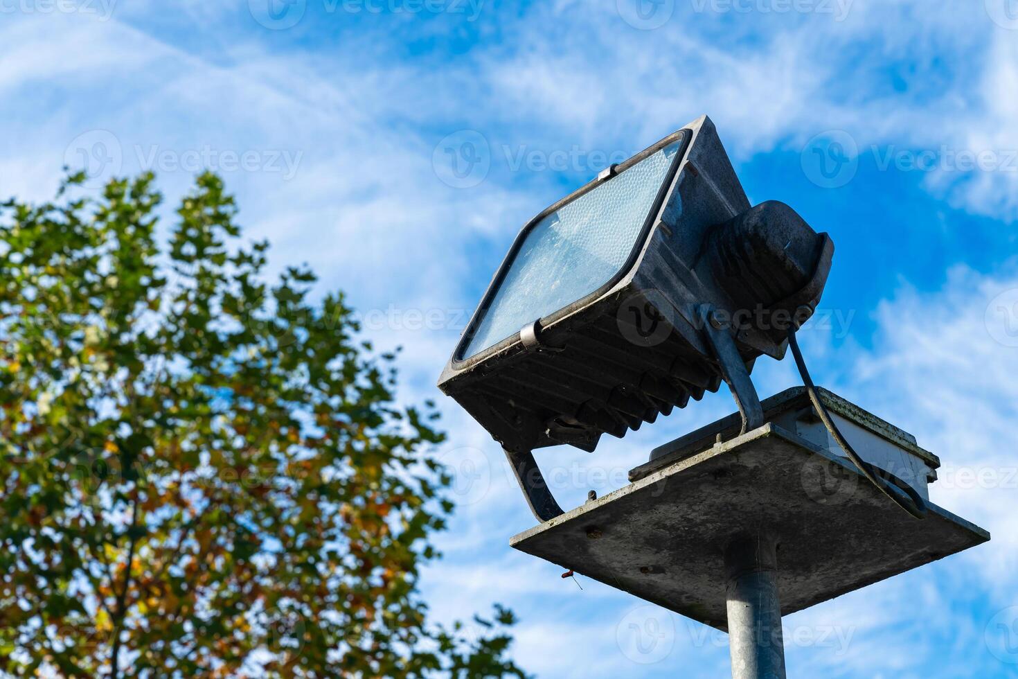 A floodlight mounted on a pole against a blue sky in autumn photo