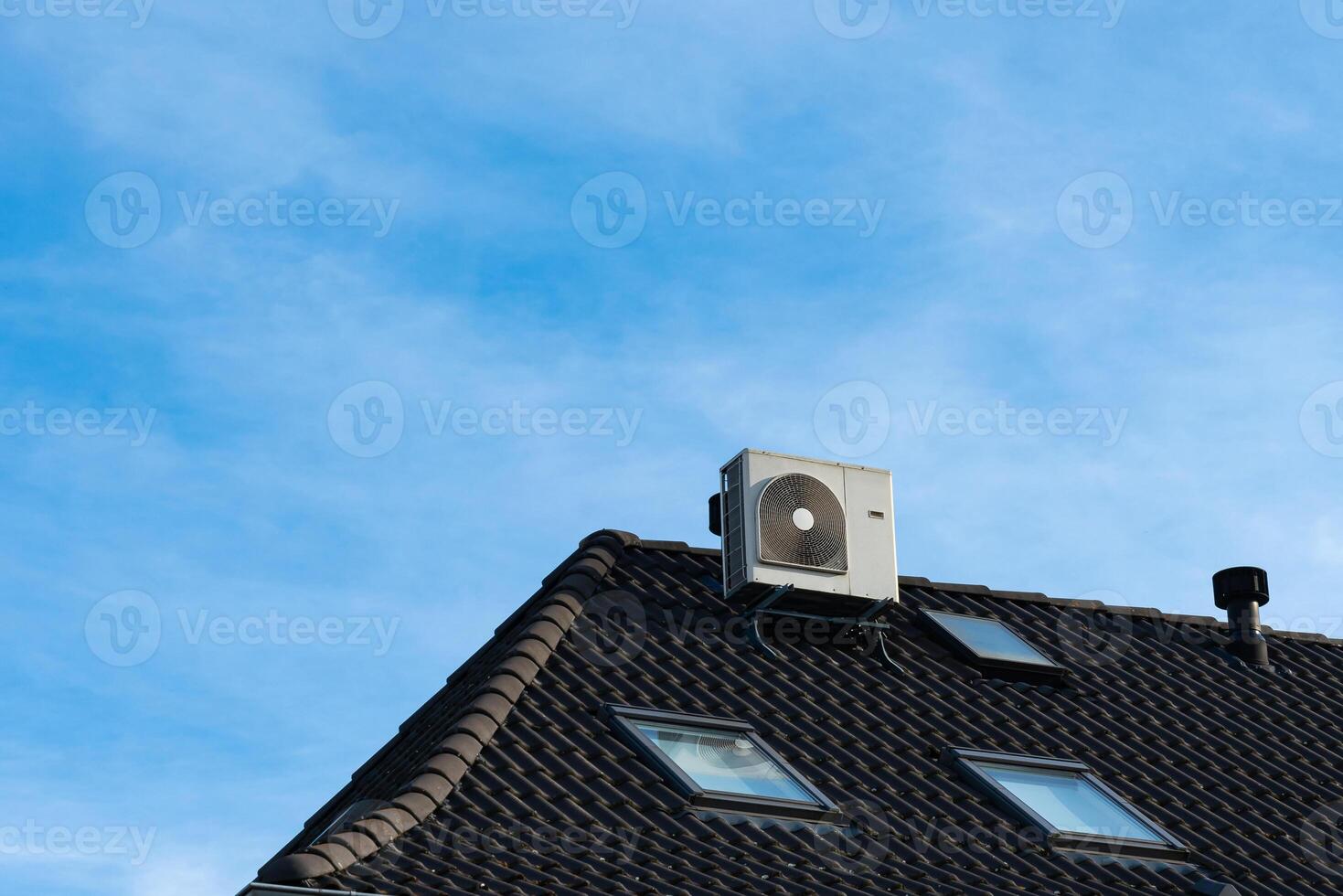 Air conditioning unit mounted on a rooftop under a clear blue sky photo