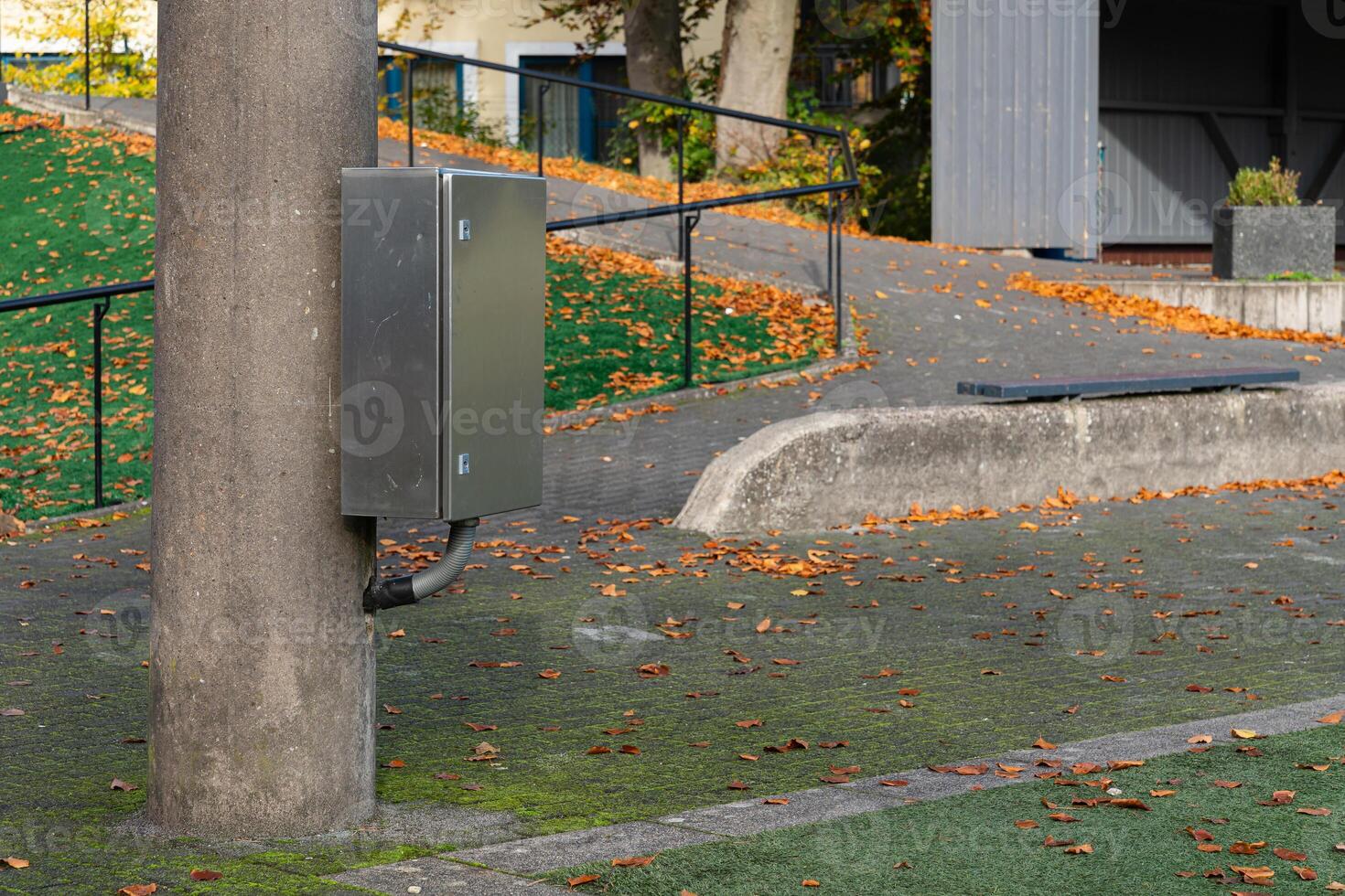 Metal utility box attached to pole in a park during autumn photo