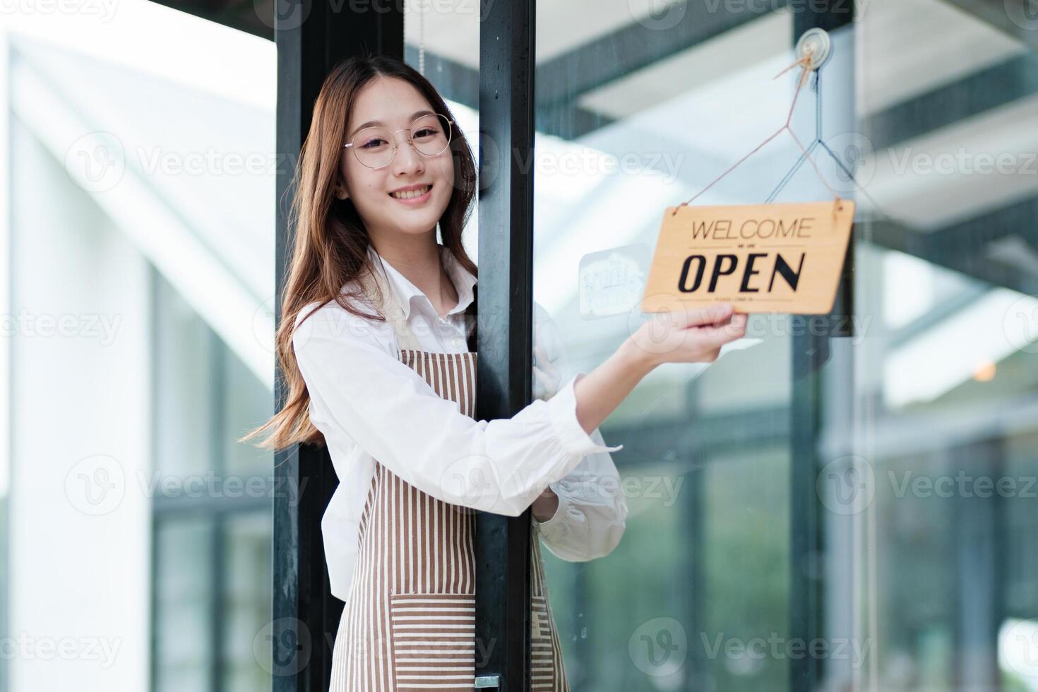 Shopkeeper flipping an open sign at the storefront, signaling the start of the business day. photo