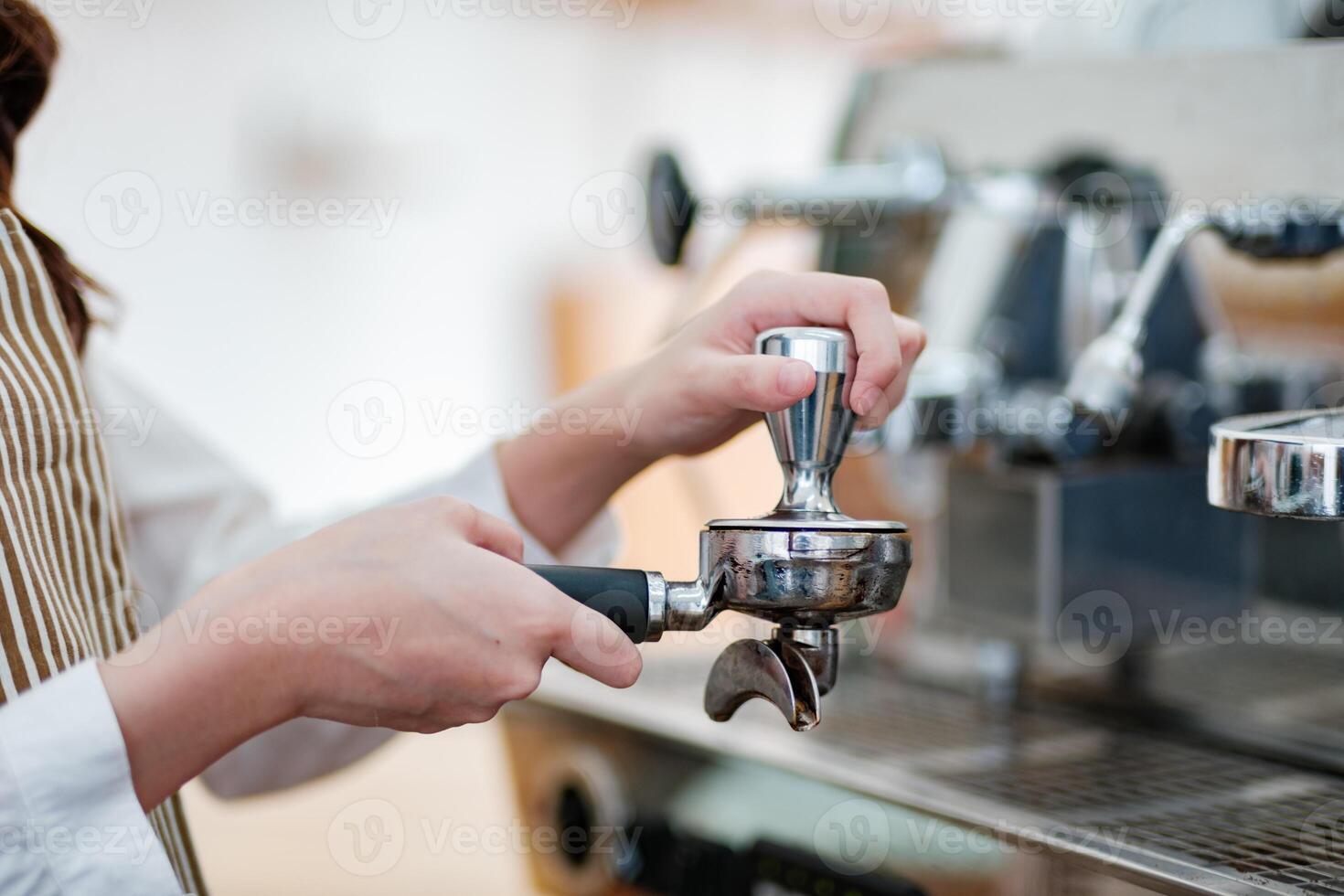 Barista tamping espresso grounds, showcasing precision and professionalism in a cafe setting. photo