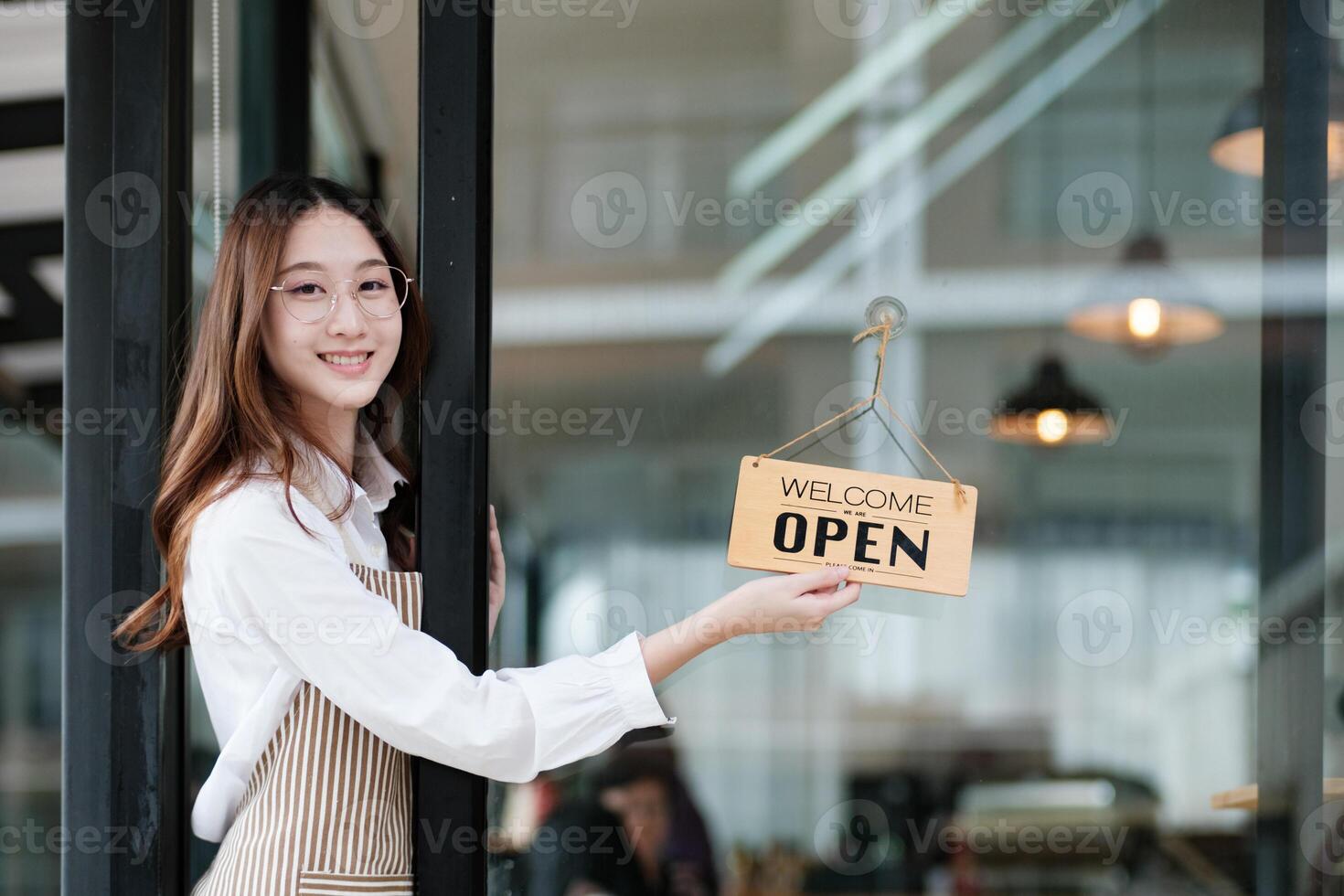 Shopkeeper flipping an open sign at the storefront, signaling the start of the business day. photo