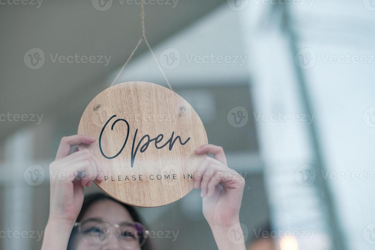 Shopkeeper flipping an open sign at the storefront, signaling the start of the business day. photo